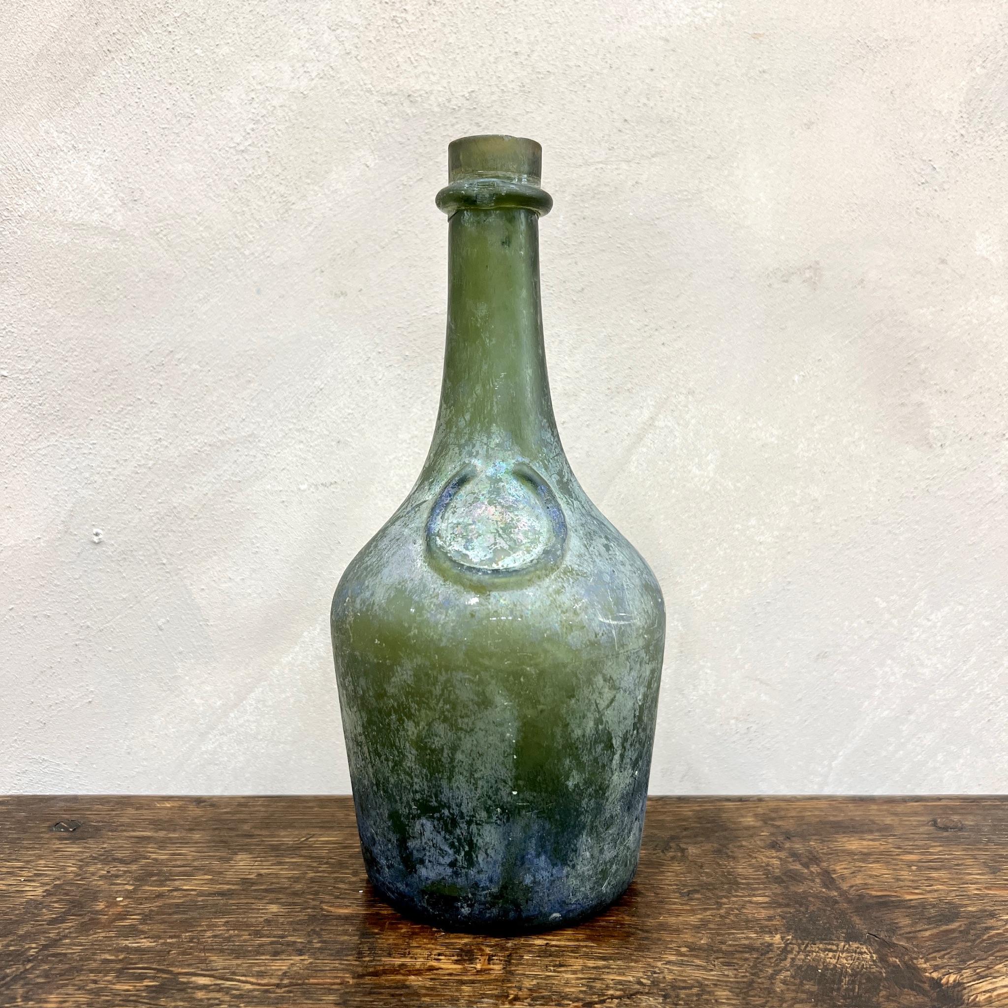 Green iridescent glass, maritime bottle.
Undoubtedly submerged under the water for many years.
Exceptionally deep punt.

France, circa 1760.

Height: 26.5cm
Dia: 13cm
Base Dia: 10cm

Please message if any further info or photos are required 

We are