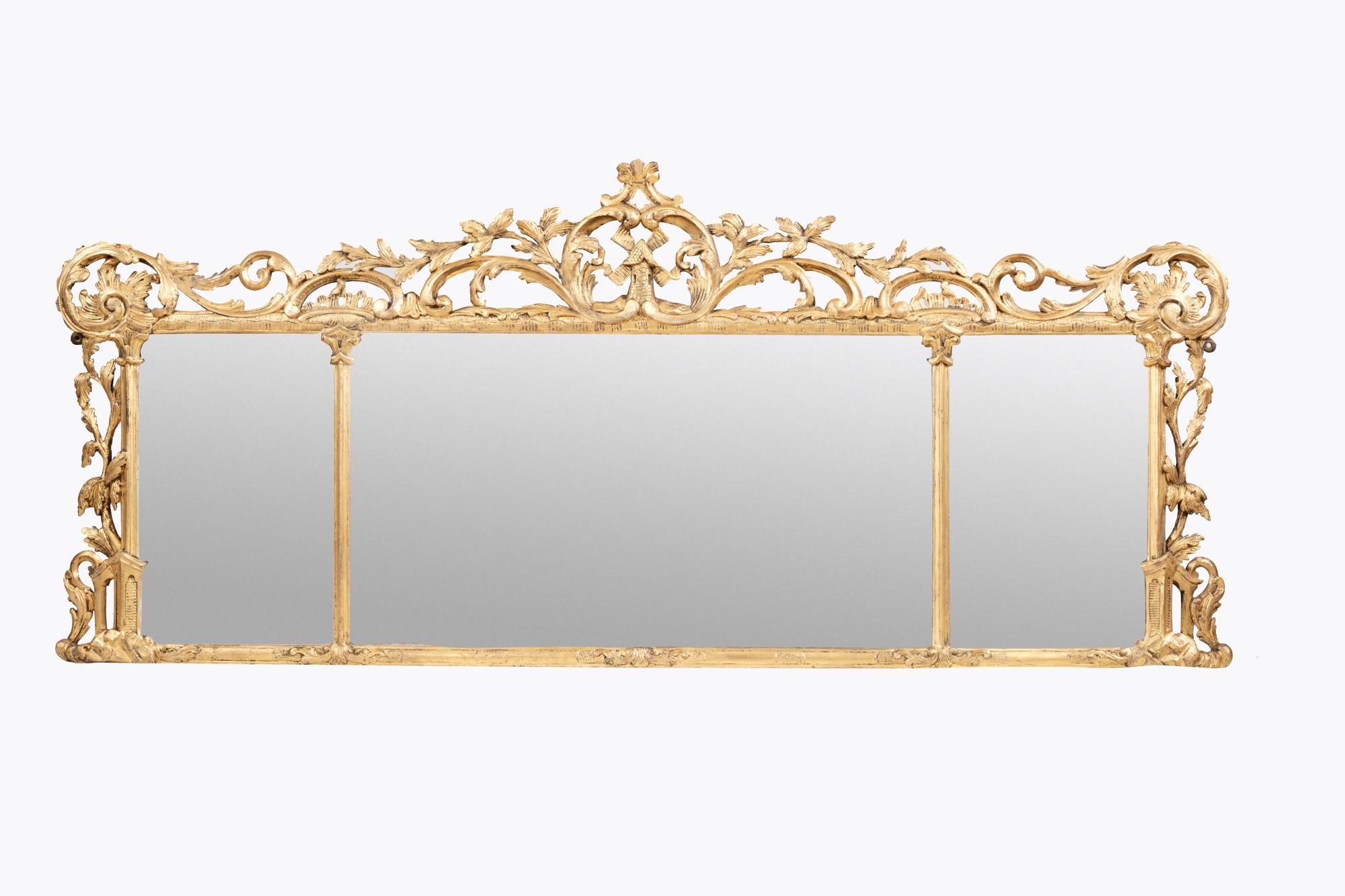 Giltwood compartmental overmantle mirror in the manner of Chippendale. The period glass plate divided by stylised columns sits within a highly carved giltwood frame. The centrepiece features a windmill surrounded with foliate detail, scrolls and