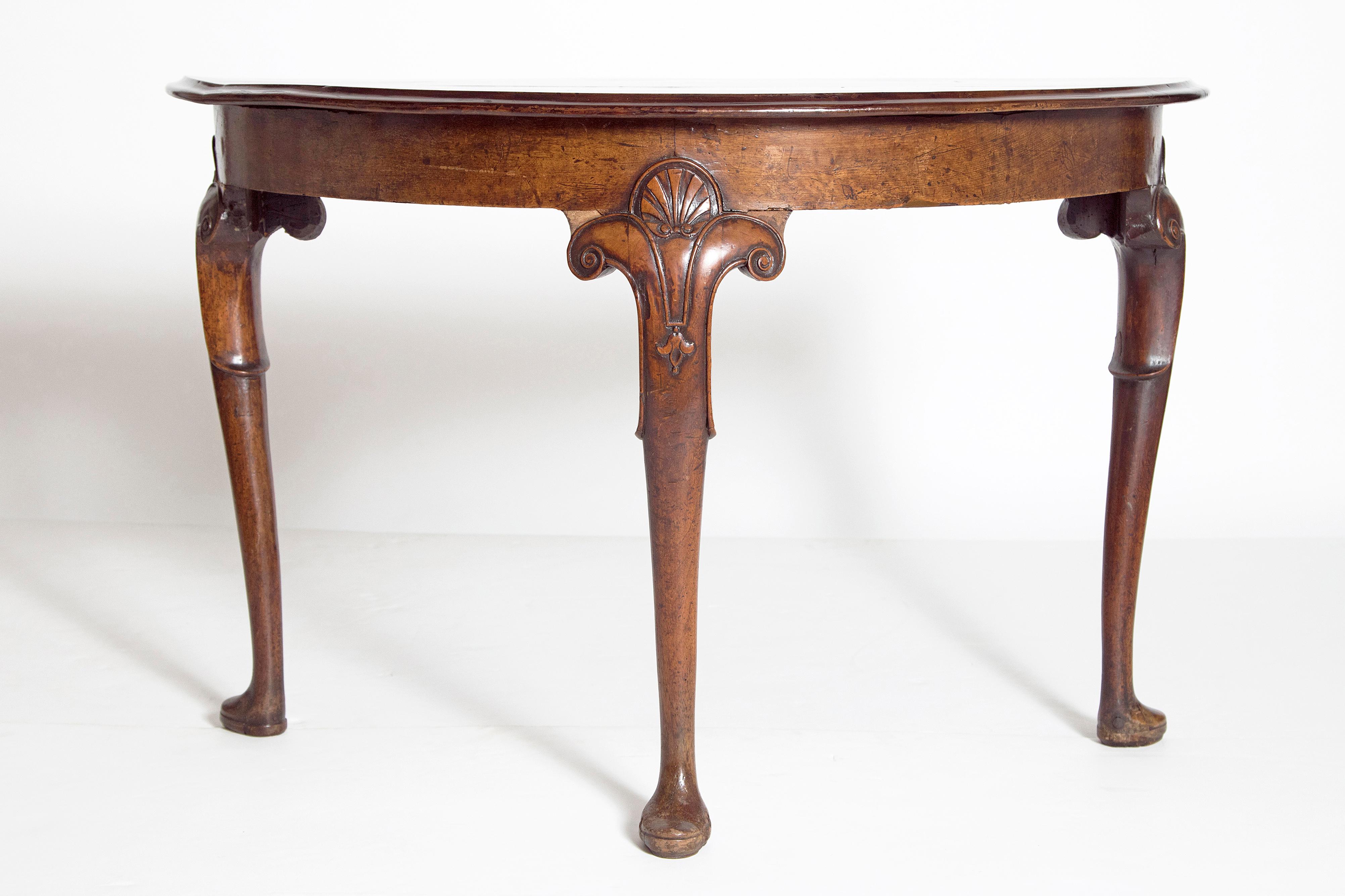 A lovely walnut demilune with three cabriole legs resting on pad feet. The two back legs are turned to the rear. The apron is burl and the knees of the legs are carved with a shell and curls. Ireland, circa 1720.