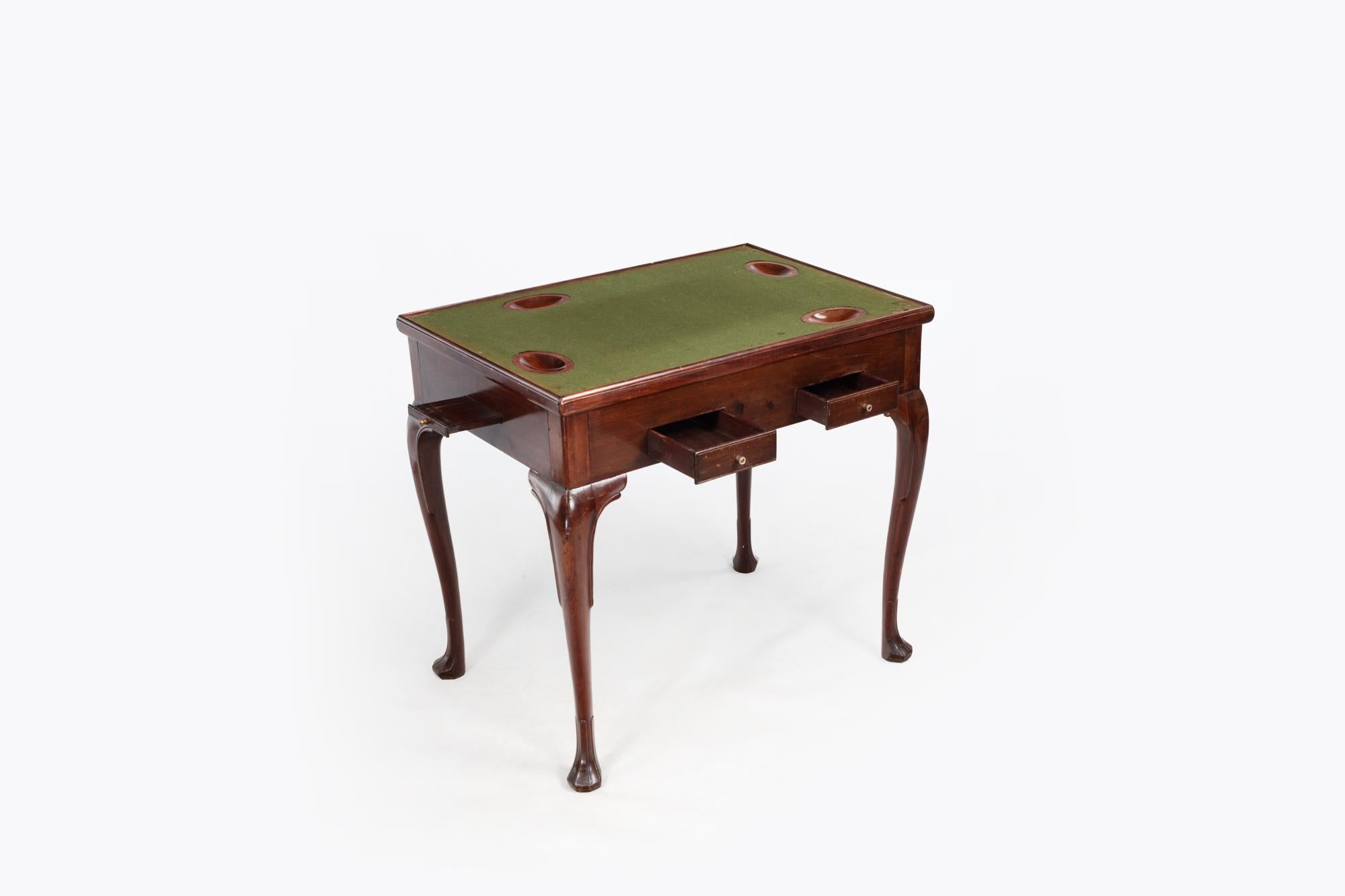 18th Century Irish Georgian mahogany games table featuring lift-off rectangular top. The reversible rectangular dished top with baise playing surface and sunk counter wells sits above the frieze containing fitted pull-out candle and counter slides.
