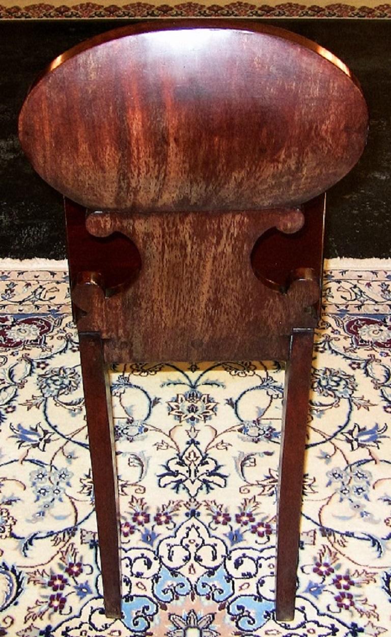 Gorgeous Irish mahogany hall chair from circa 1790.

Fluted legs with gorgeous scallop shell scrolled back and armorial plate.

Made of the best Cuban mahogany. It sits on four legs. The front two are beautifully turned and fluted and the back