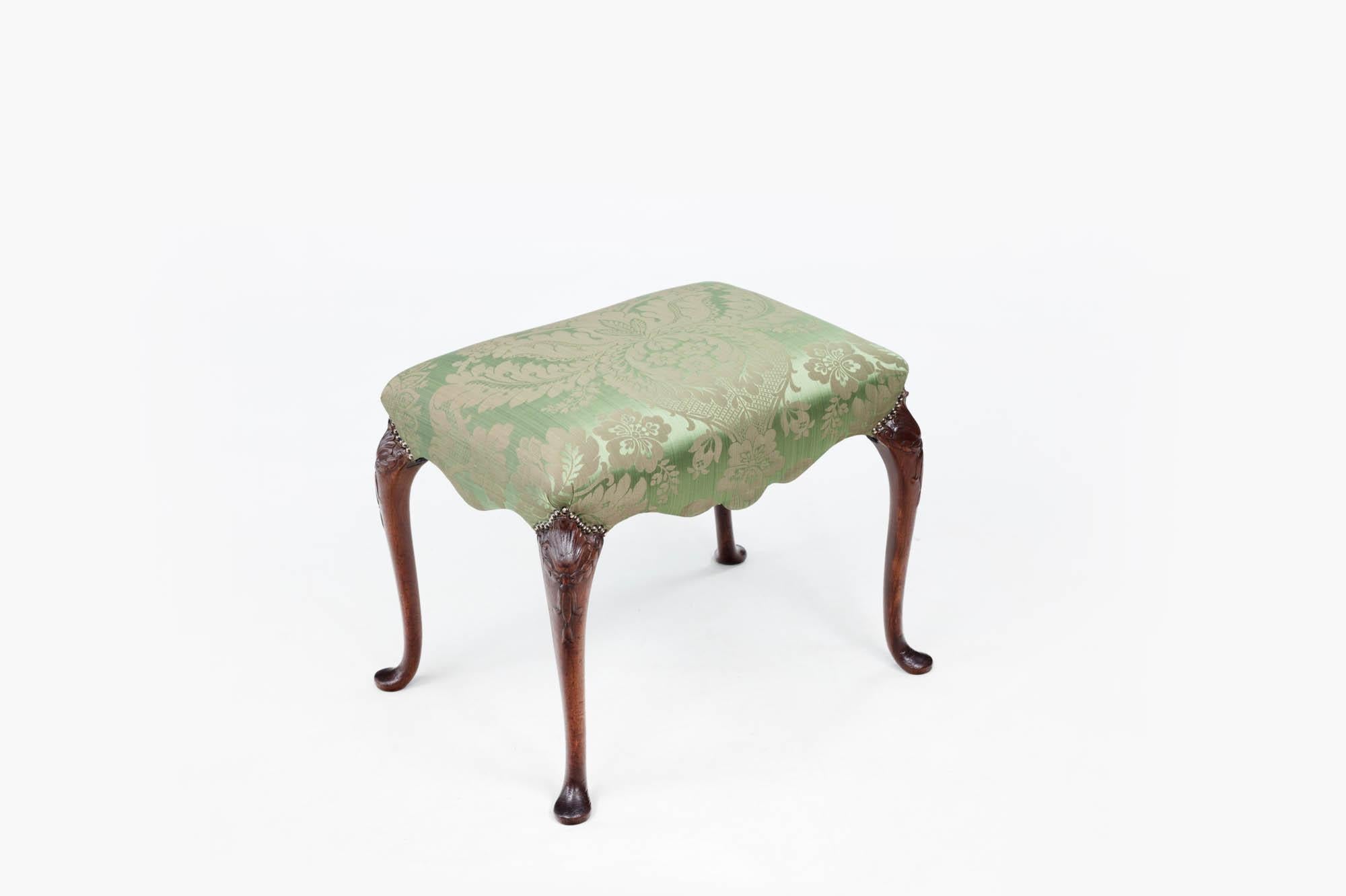 18th Century Irish Georgian stool with unusual serpentine-shaped rail and raised on acanthus carved cabriole legs terminating on slipper feet. This piece has recently been reupholstered in fine green damask.