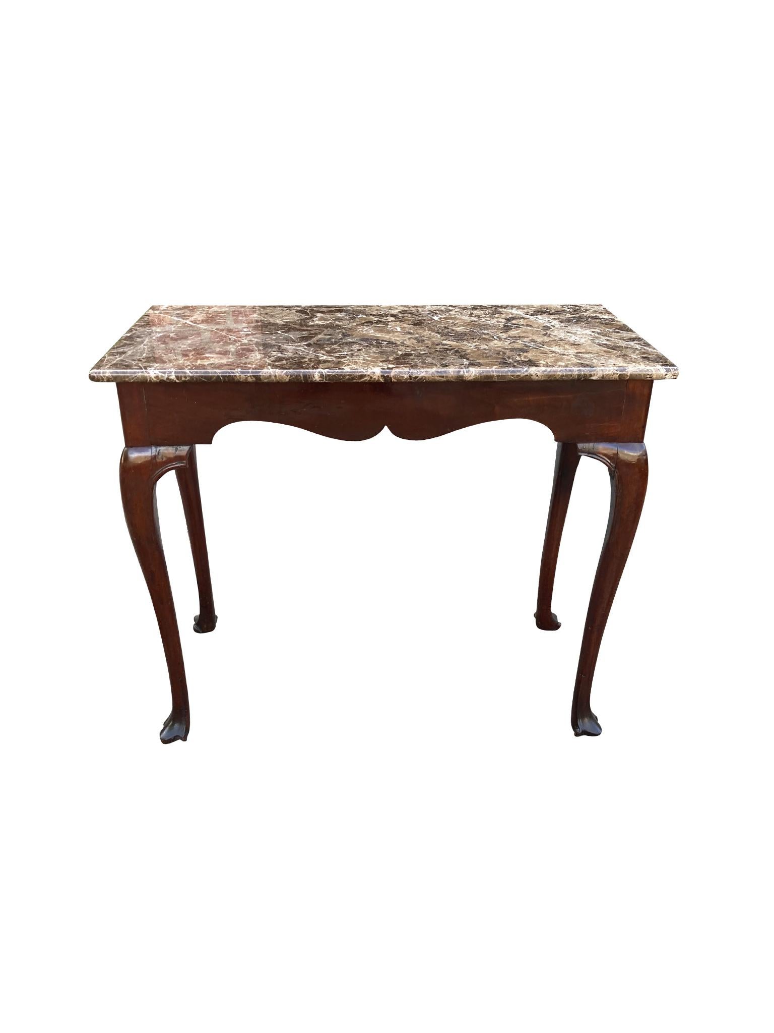 Antique Irish console table, crafted in the 18th century. This elegant piece is comprised of a hardwood base and a marble table top. Its design is one of symmetry and balance: thin cabriole legs that curve upward to a front skirt fashioned into a