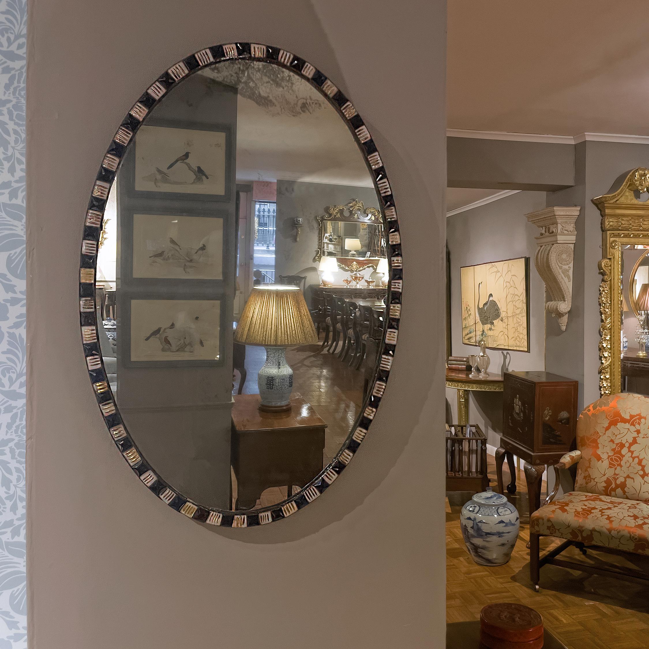 This Irish George III mirrors consists of an oval mirror plate surrounded by alternating blue and clear faceted cut glass gems (with applied gilding), set into a metal frame. County Waterford was famed for its glass production in the 18th and 19th