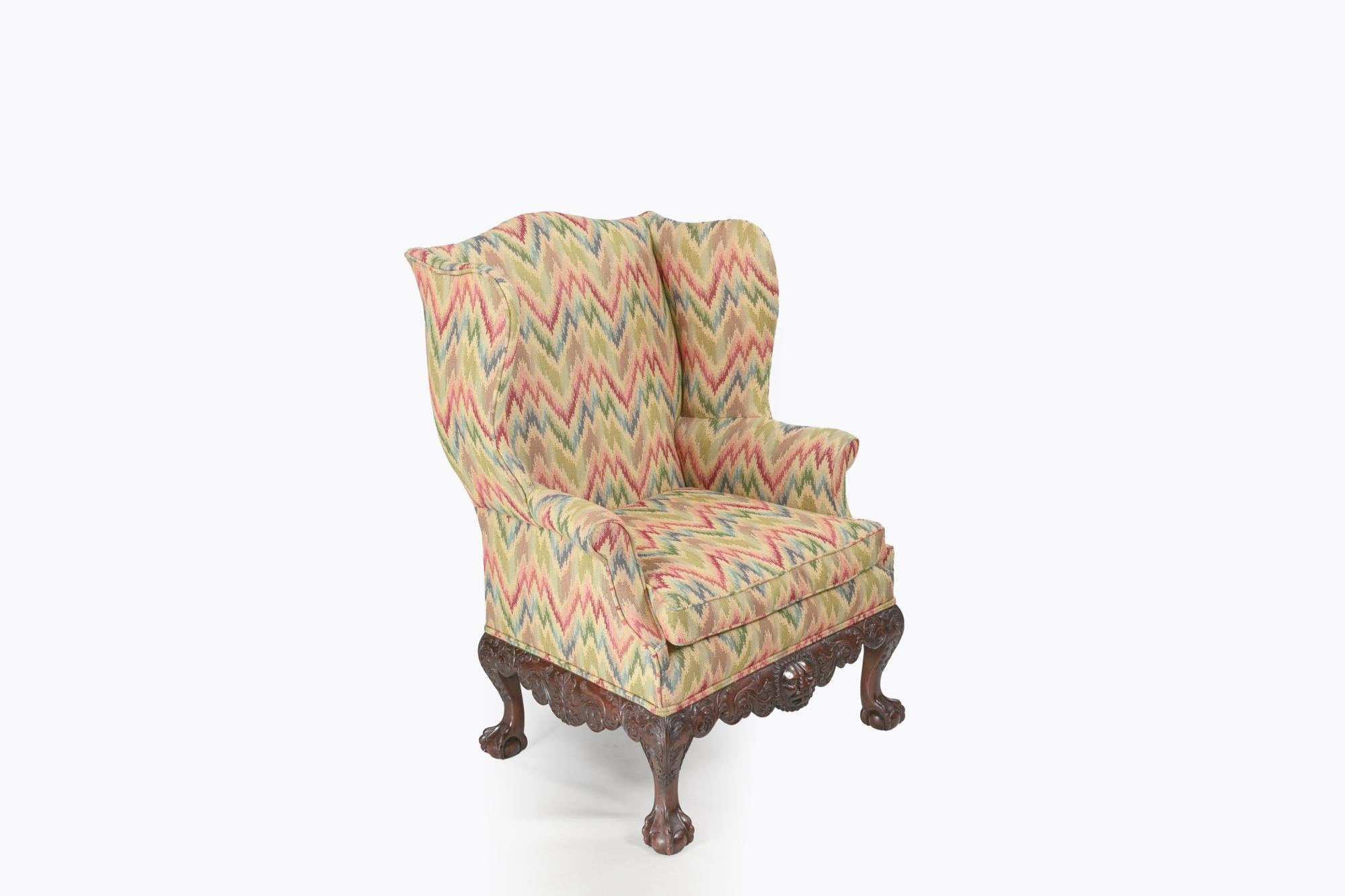 Chaise à oreilles irlandaise du 18e siècle Tablier en acajou sculpté de motifs feuillagés et d'un motif central en forme de tête de lion. Elle repose sur des pieds cabriole qui se terminent par des pieds boule et griffe.
