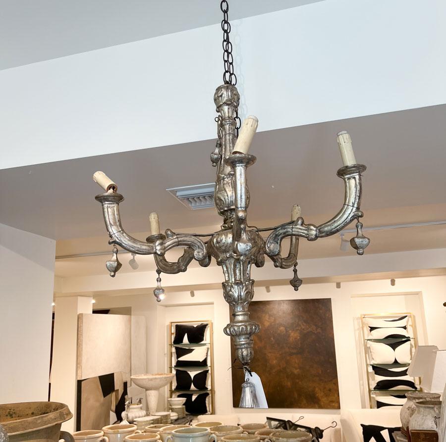 Questo magnifico lampadario è caratterizzato da sei bracci graziosamente curvi, ognuno dei quali è impreziosito da dettagli delicati e da una lussuosa finitura in foglia d'argento. L'applicazione della foglia d'argento, eseguita meticolosamente a