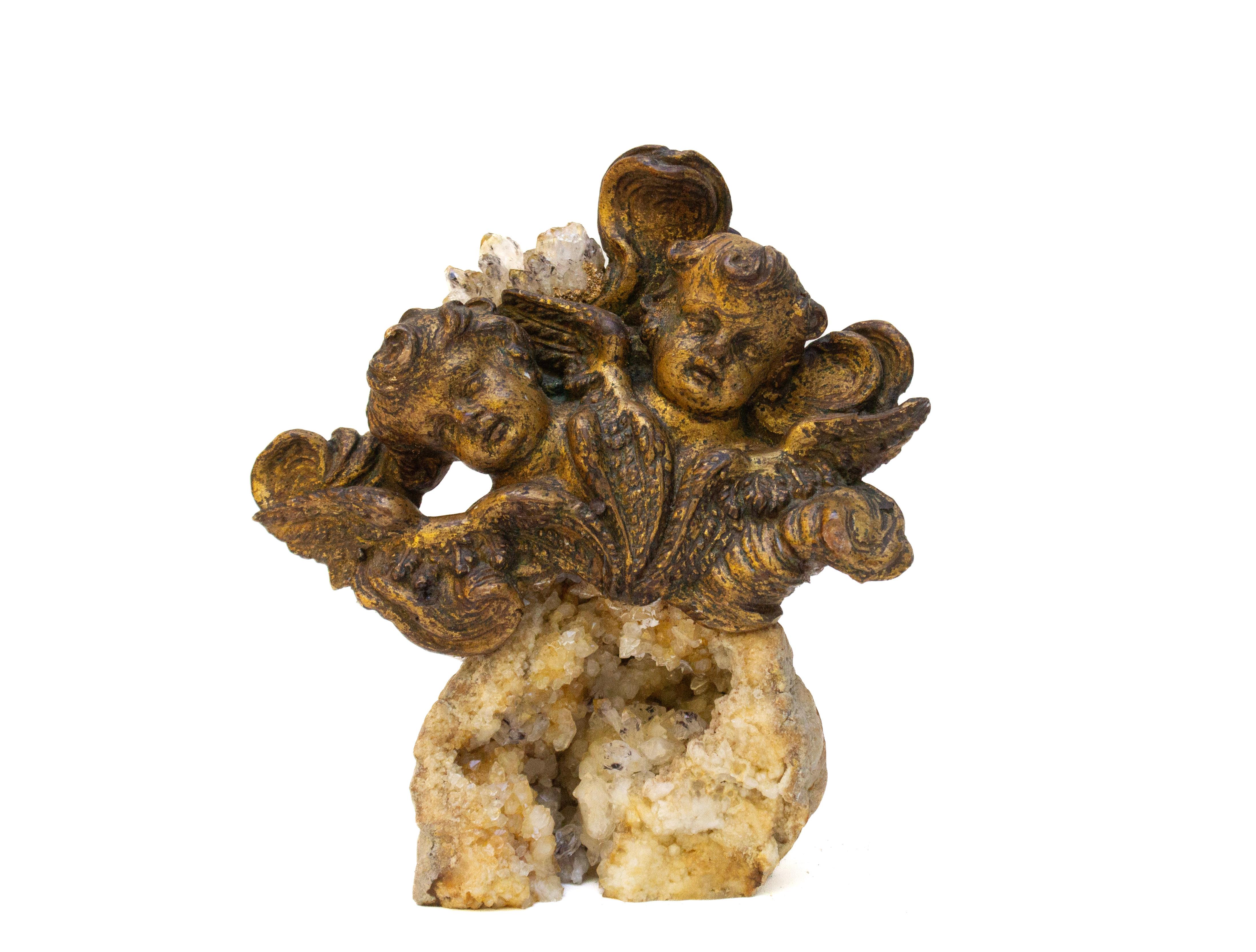 Têtes d'ange italiennes du 18e siècle sculptées à la main sur une géode de cristal assortie.

Les anges faisaient autrefois partie d'une représentation céleste et angélique dans une église historique en Italie. Les Nature ont été ornées de cristaux