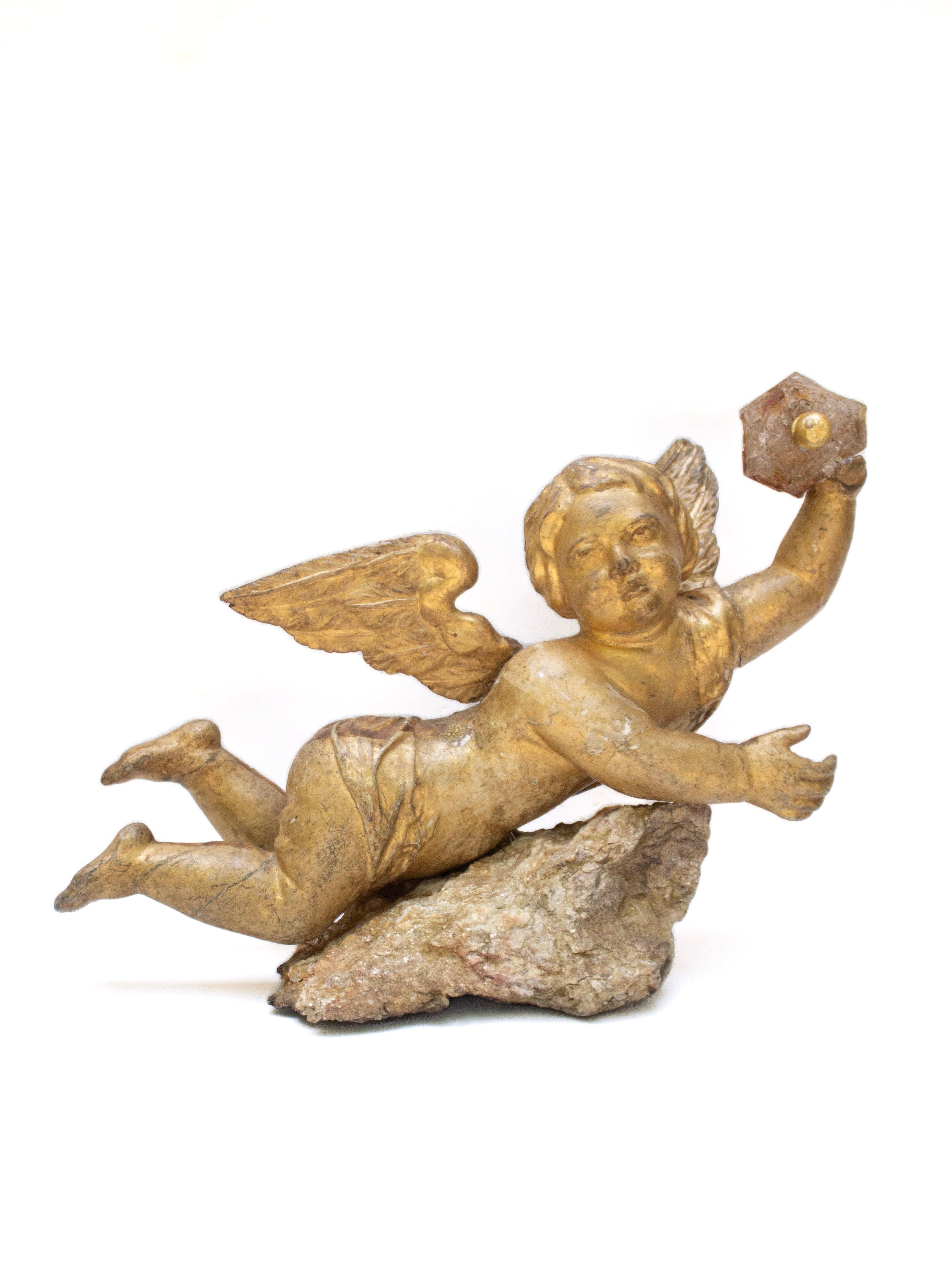 Italienischer, handgeschnitzter Engel aus dem 18. Jahrhundert, der in einer Hand einen Herkimer-Diamanten mit einer einzelnen Goldperle in der Mitte hält und auf einem koordinierten Goldglimmer in Matrix ruht.

Das Engels-Artefakt war einst Teil