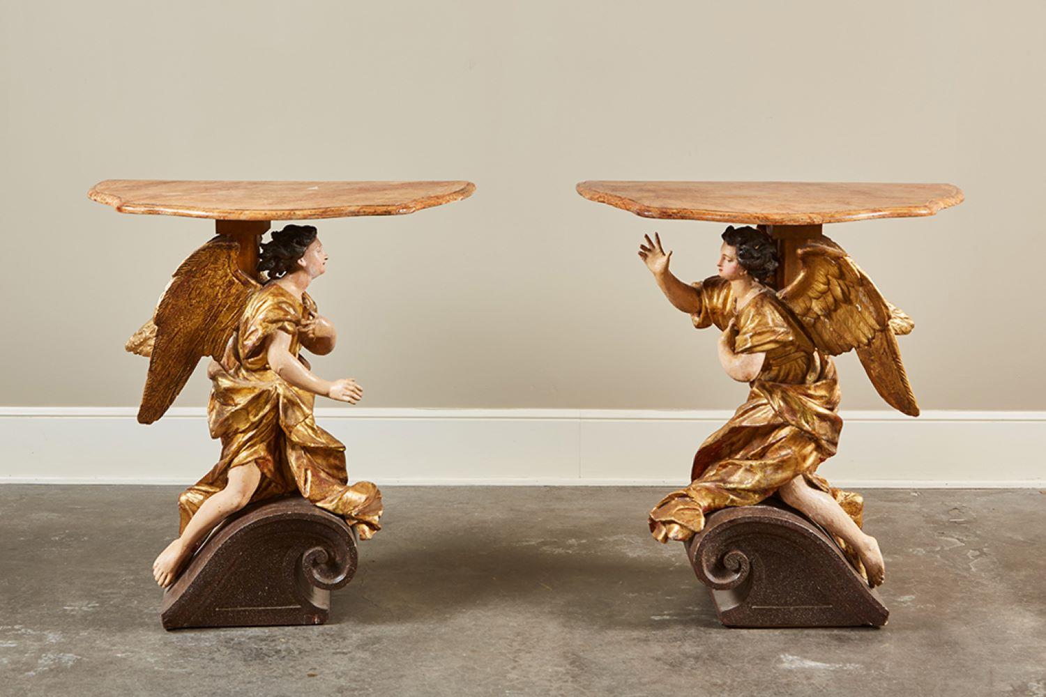 A lovely pair of 18th century Italian Baroque console tables adapted from carved gilt and painted wood angels that were originally architectural elements attached to a basilica wall. Posed on the scrolled halves of a pediment, the winged angels are