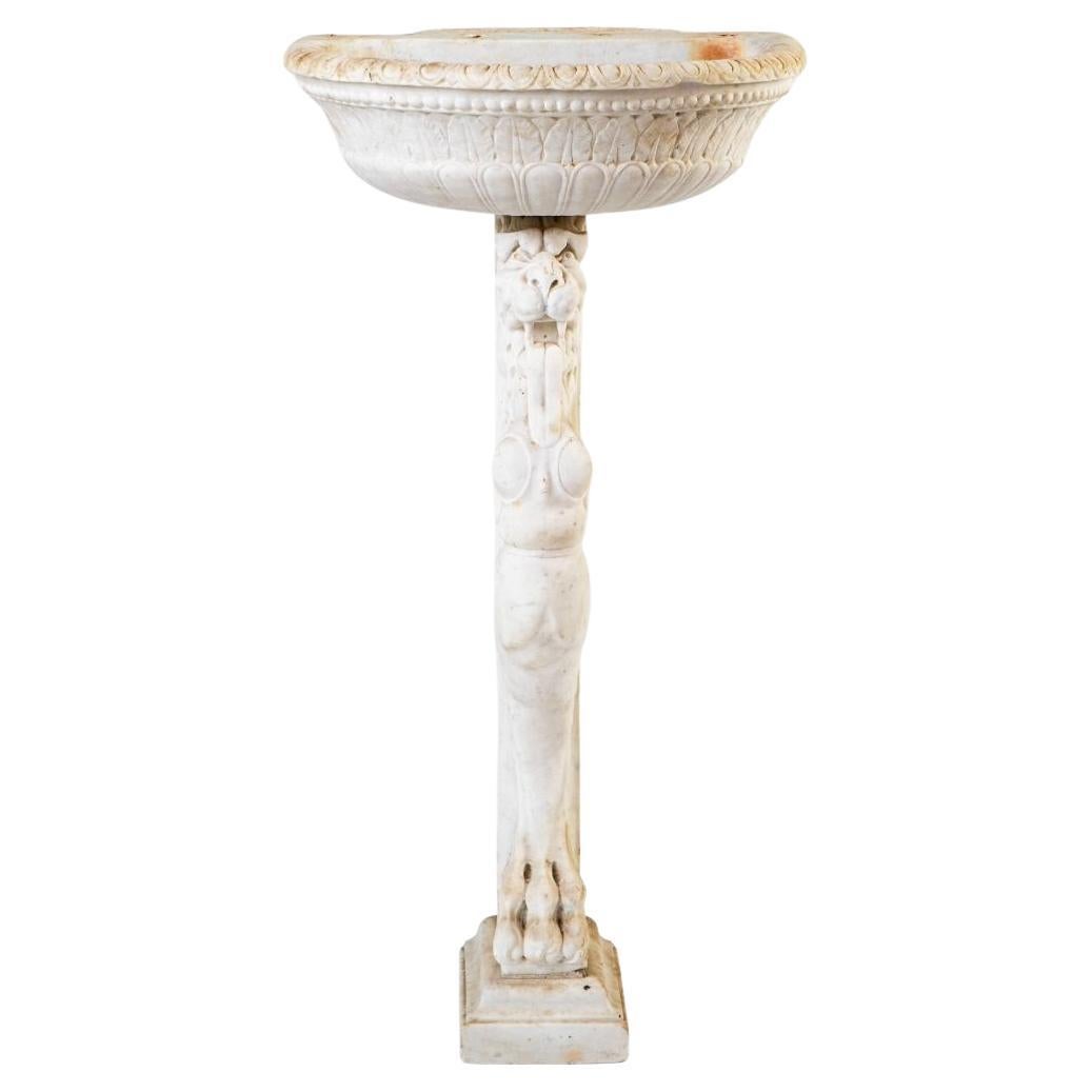 A decorative and charming Italian Baroque basin, crafted in fine white Carrara marble with fine hand-carved detailing throughout both the basin and pedestal.

The basin is adorned with carved acanthus leaf motifs in true Baroque style.  The bust is