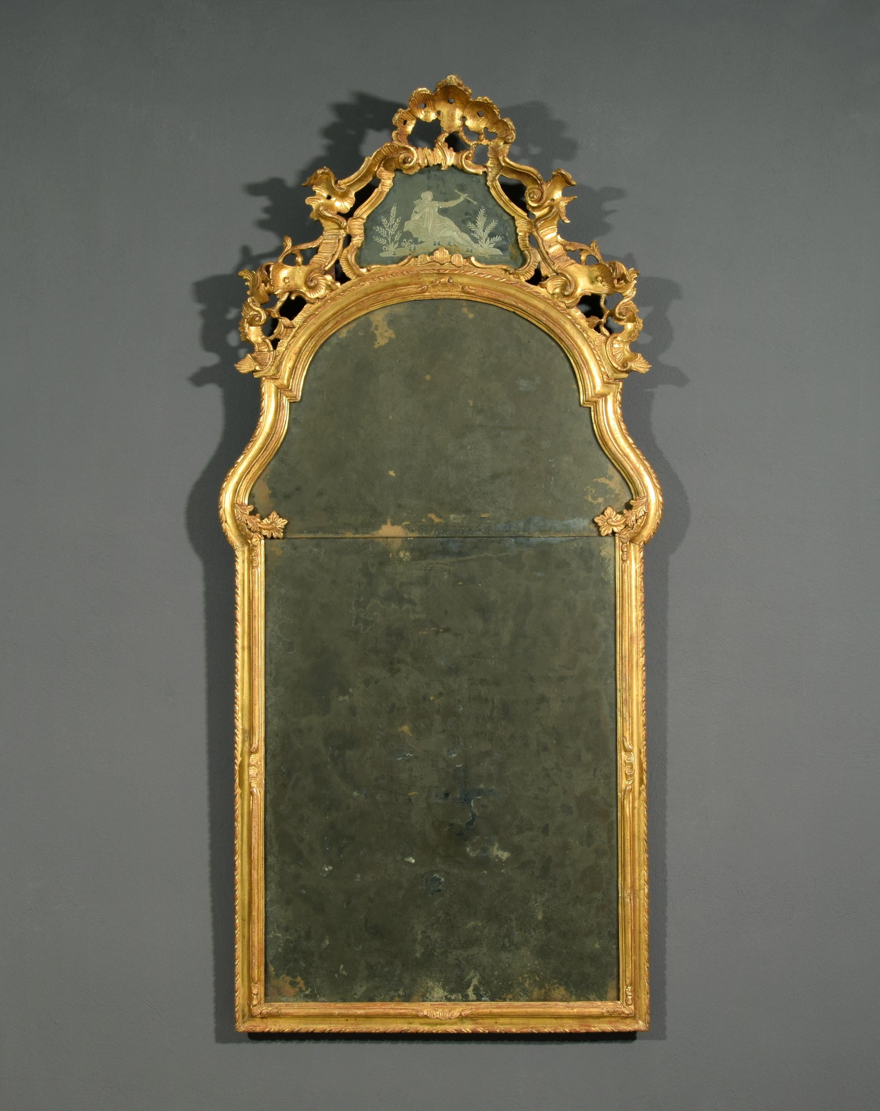 18th century, Italian baroque carved and giltwood mirror 

This refined mirror was made in Venice, Italy, in the eighteenth century and has the characteristic decoration of the Venetian Baroque.
The mirror, in carved and gilded wood, has an