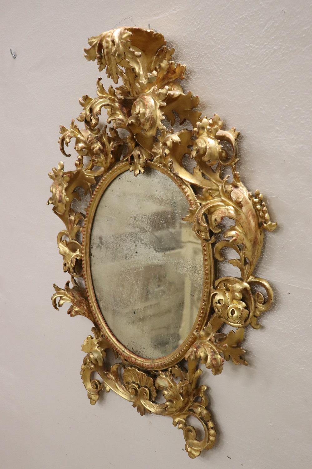 Sehr wichtiger, schöner und eleganter ovaler Wandspiegel aus der Barockzeit, 1750. Ganz aus geschnitztem und vergoldetem Holz mit Blattgold. Der reiche Schnitzdekor mit Voluten und Akanthusblättern, die sich auf der Vorderseite aufrollen, wird