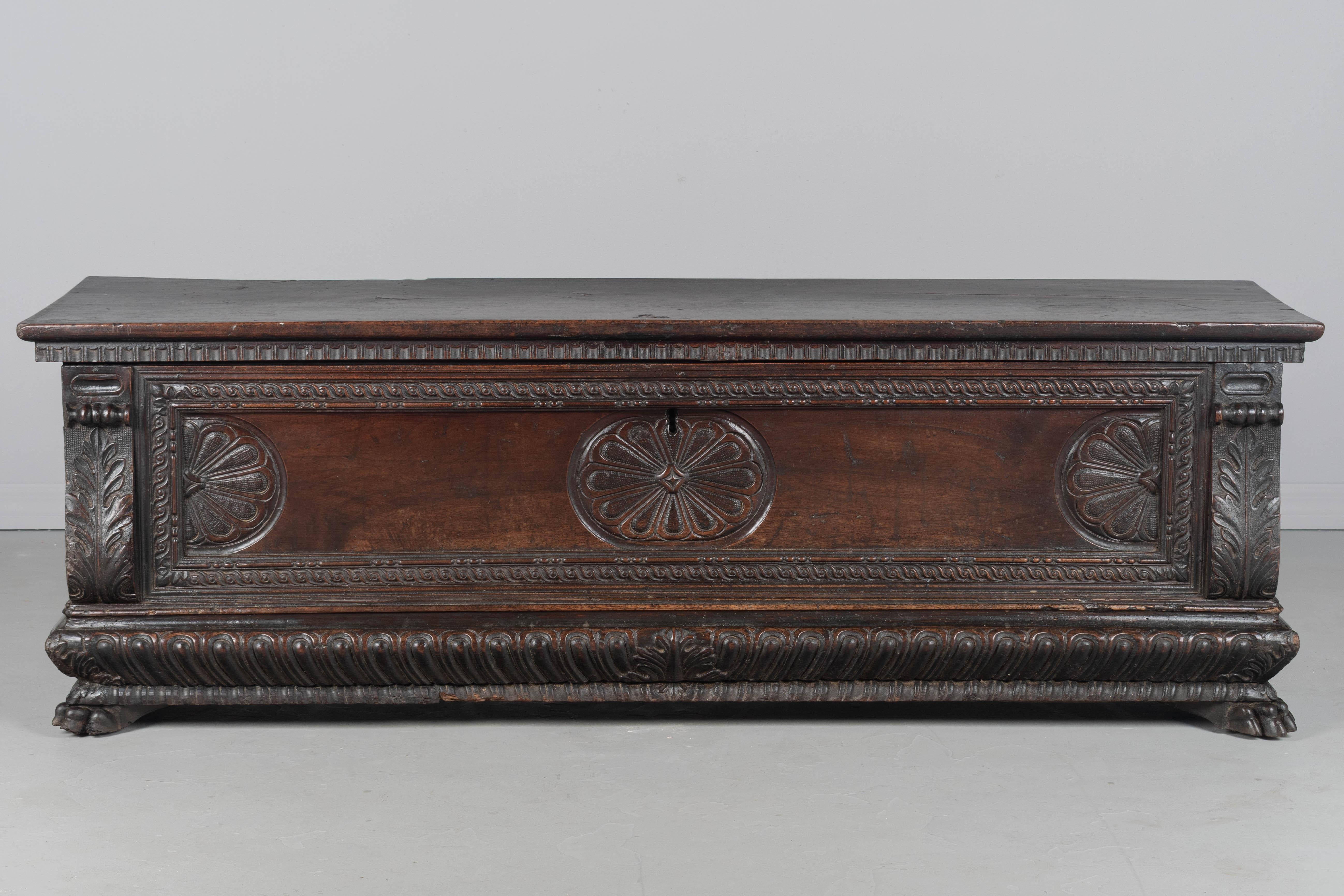 Fino cassone o arcón matrimonial barroco italiano del siglo XVIII, de estilo renacentista, hecho de nogal macizo. Los atrevidos detalles están tallados a mano en altorrelieve e incluyen un panel central con rosetas, esquinas de hojas de acanto con
