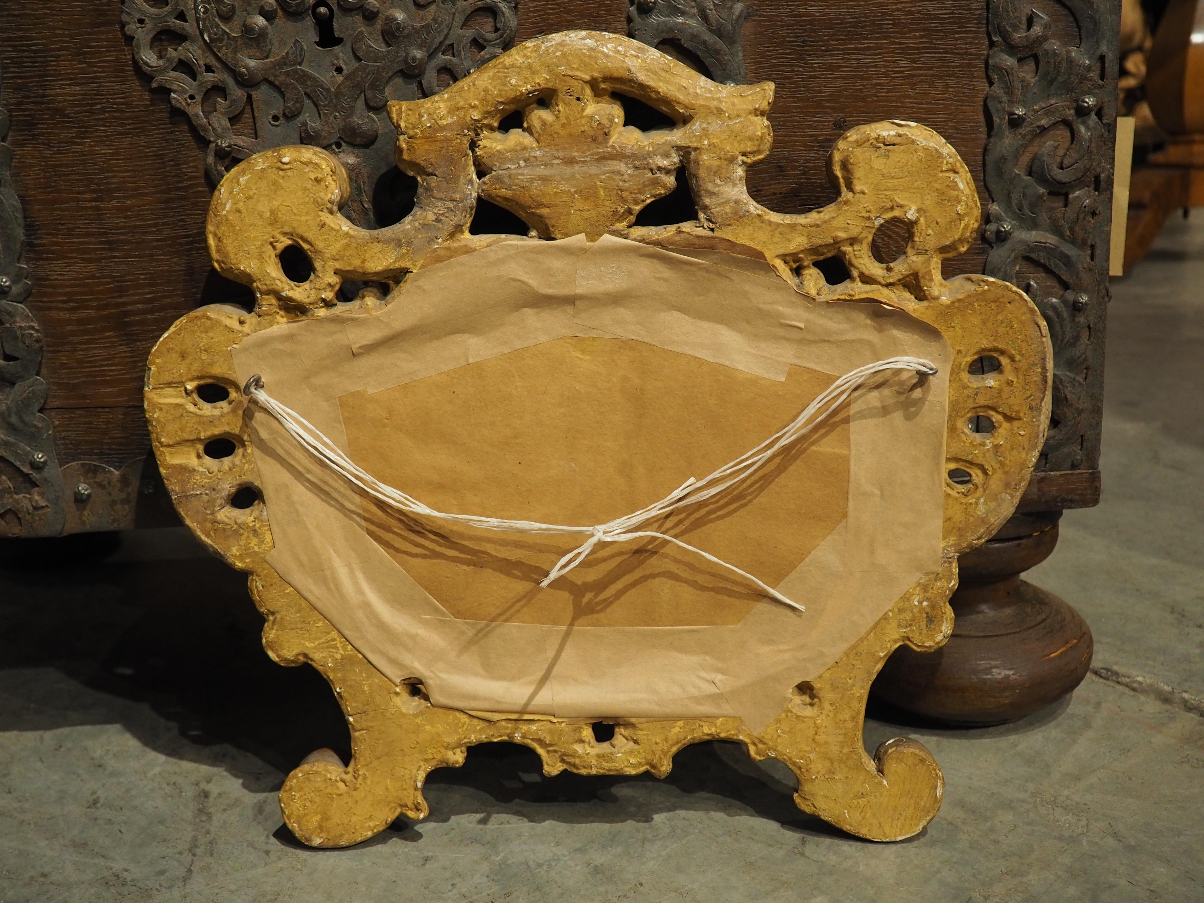 Dieser um 1750 in Italien handgeschnitzte barocke Kartuschen-Spiegel aus vergoldetem Holz zeigt ein geformtes Stück Glas, das von einer schönen goldenen Kartusche mit durchbrochenen Elementen umgeben ist. Die Schnitzereien sind von der Natur