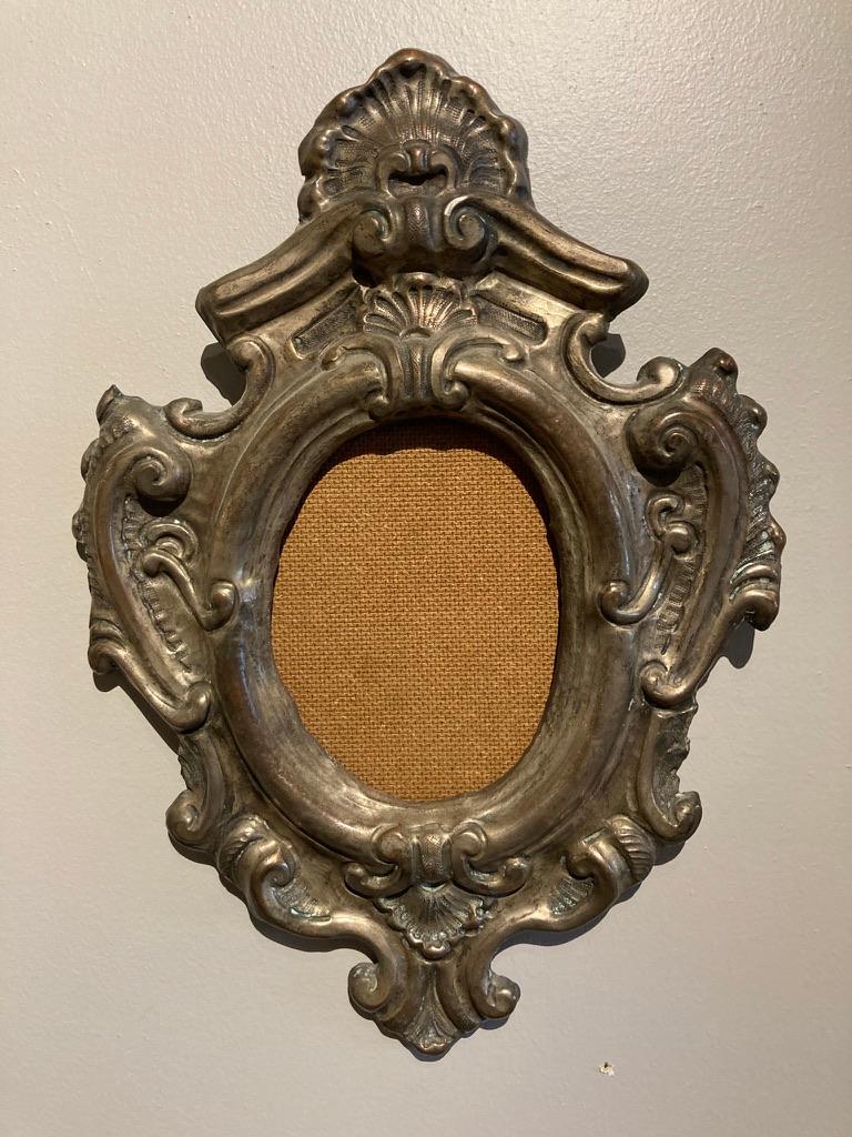 This original 18th century silver gilded over brass frame is elaborately embossed and chiseled. The central oval is surrounded by rocaille and volute motifs typical of the Baroque period. This will make a unique frame for a favorite photograph,