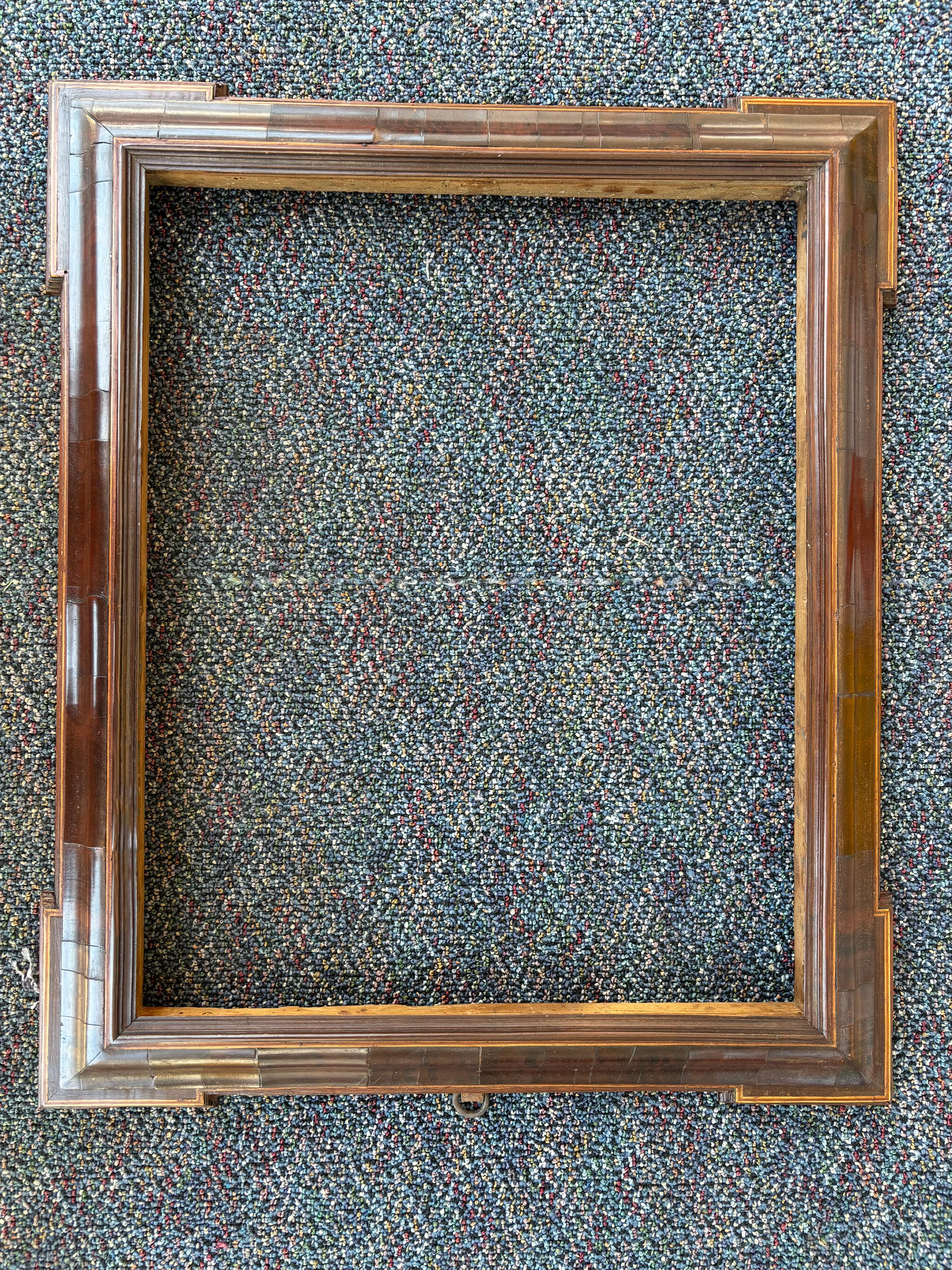 Barroco italiano del siglo XVII, con molduras escalonadas, esquinas alargadas y marco acolchado de chapa gruesa de nogal. Bandas exteriores e interiores de taracea de madera de frutal. Es un marco estupendo para un dibujo o un cuadro pequeño de un