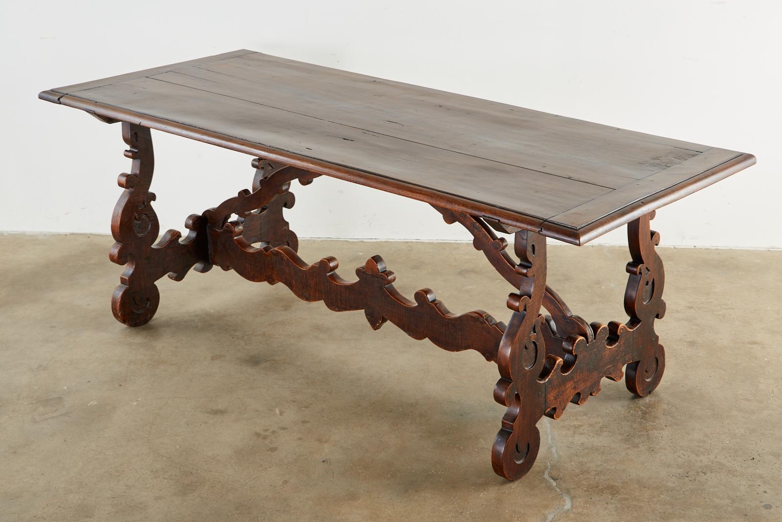 Magnificent 18th century Italian Baroque refectory table or dining table. Crafted from thick walnut planks with mortise and tenon joinery. The trestle style base is supported by carved lyre shaped legs on each end decorated with scroll work having