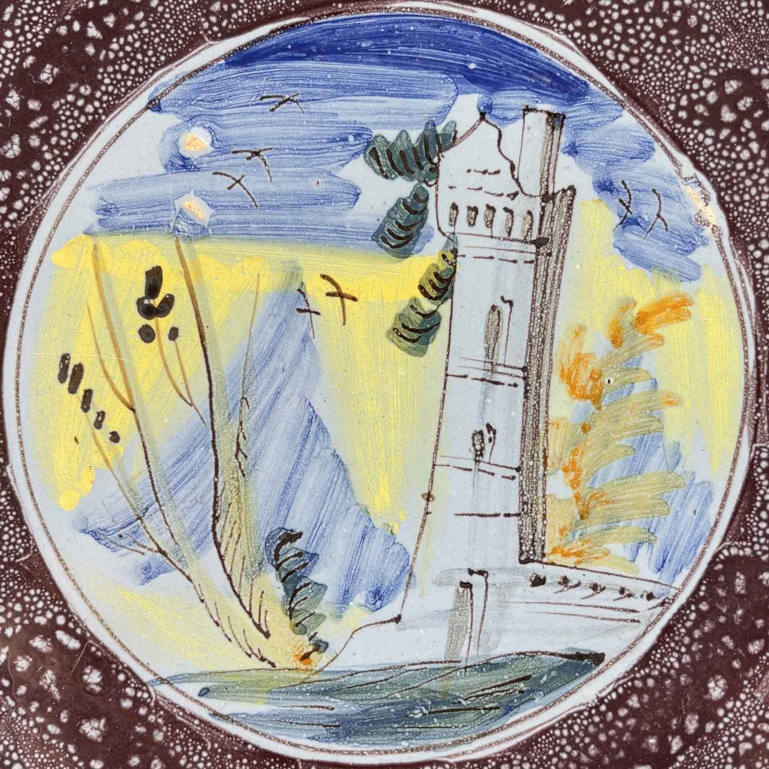 An Italian maiolica berrettino-ground riser from 18th century, central Italy, probably Faenza origin. In the central part of the riser a ruined tower is painted within a mountain landscape background; the outermost circular part is decorated with a