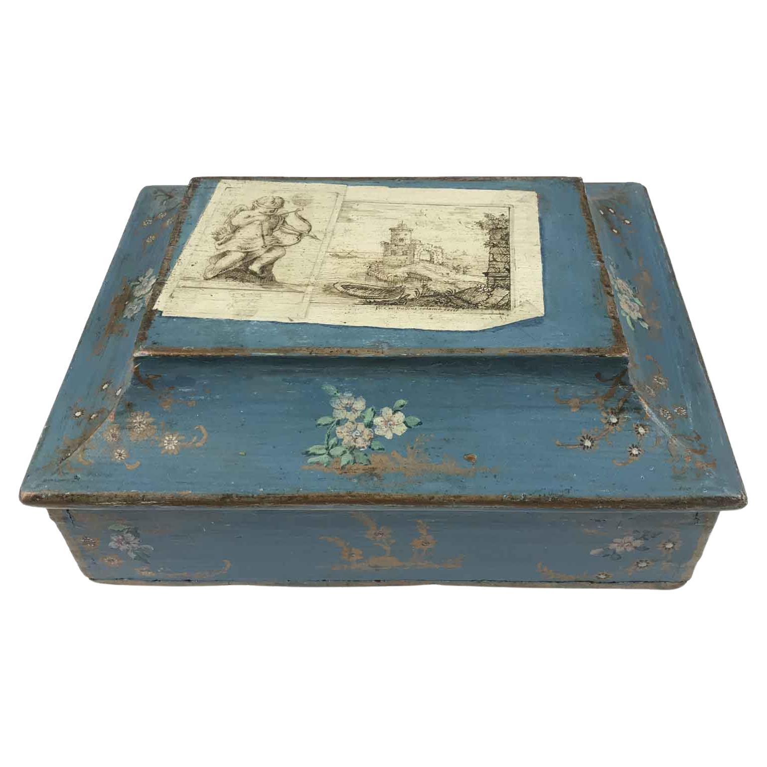 Boîte italienne en bois laqué de la fin du XVIIIe siècle avec faux papiers et fleurs. Réalisée dans des tons bleus et décorée sur toutes ses faces, cette boîte antique italienne romantique est ornée de motifs floraux et végétaux en rose et or, mais