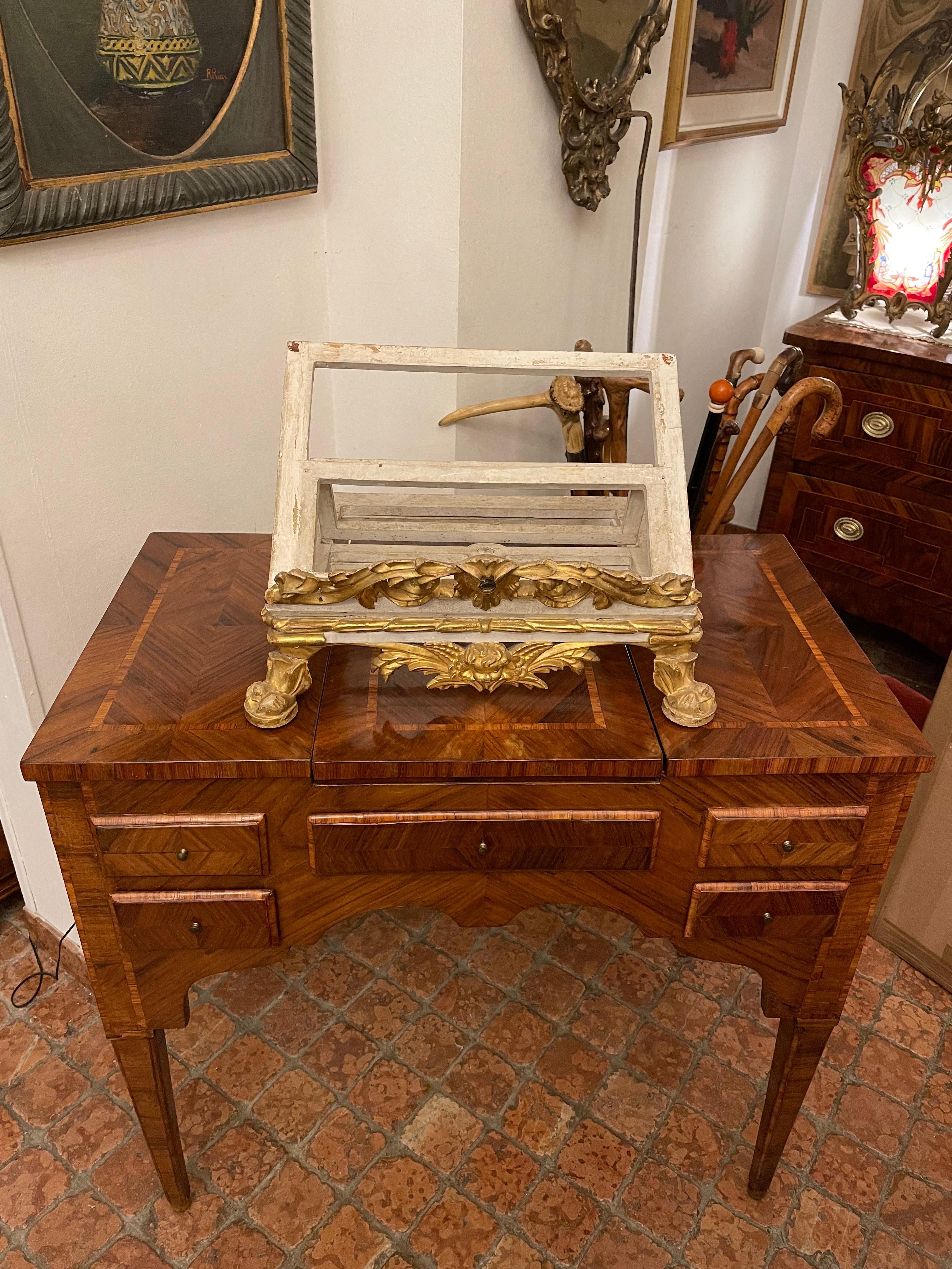 From Italy, an exclusive 18th century Louis XVI carved and gilded table lectern, an antique spruce wood bookstand or music stand carved with scrolling motifs centered by a cherub head and painted in ivory color.
This antique reading bookstand is
