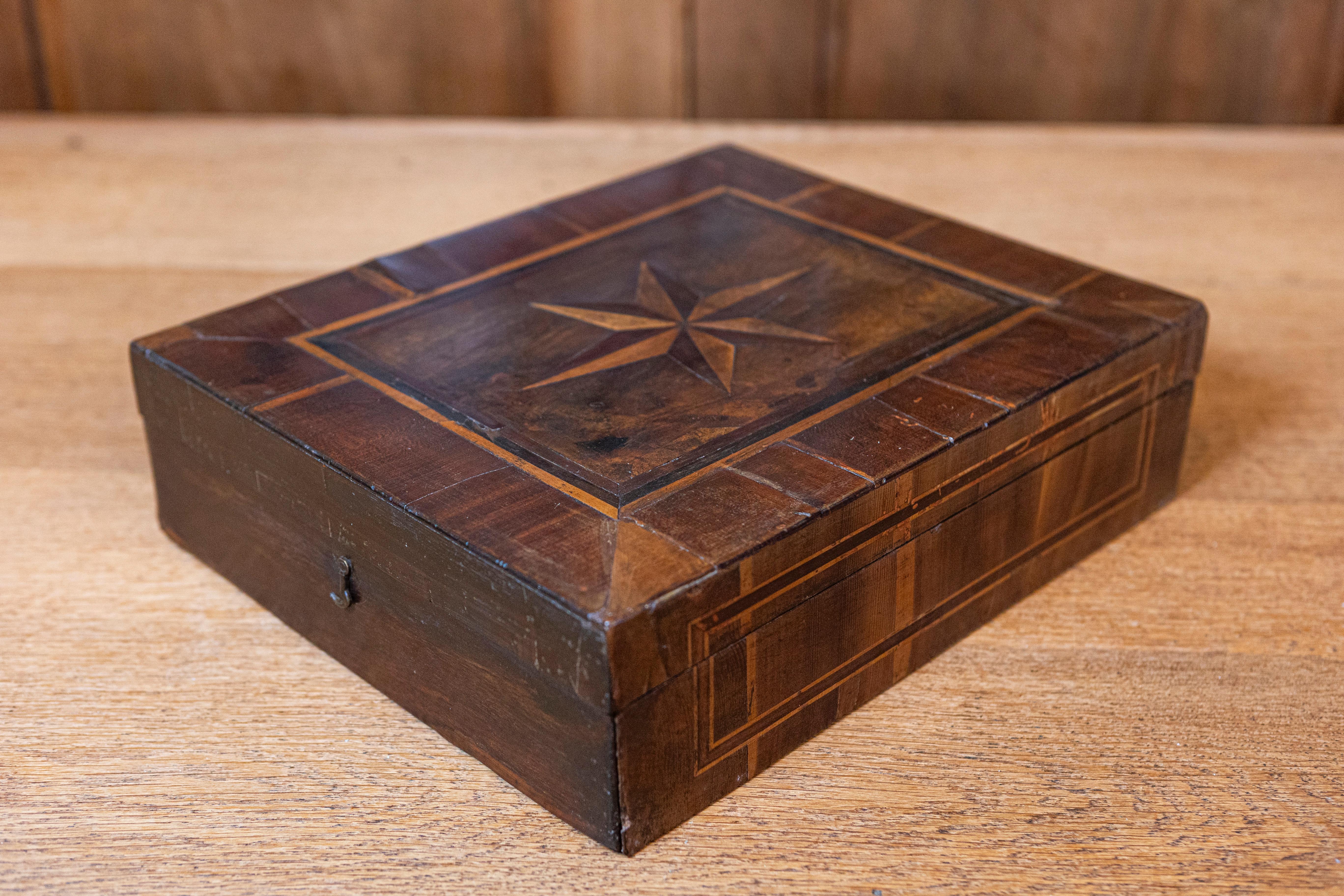 Esta impresionante caja italiana del siglo XVIII es un excelente ejemplo del arte barroco, que encarna la grandeza y la atención al detalle características de la época. Fabricada en nogal, la caja presenta exquisitas incrustaciones de marquetería y