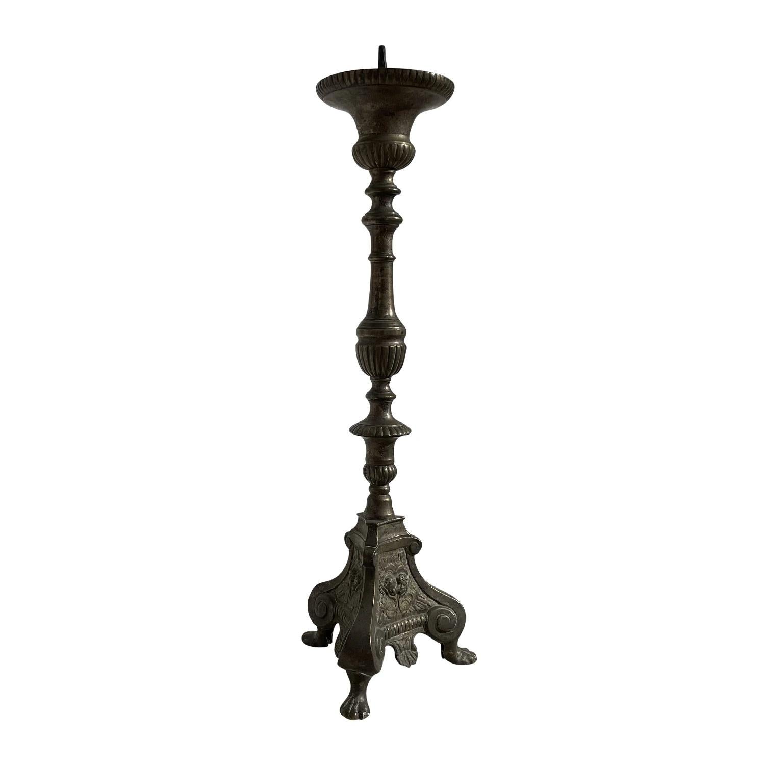 Ein antiker italienischer Altarleuchter mit religiöser Symbolik aus handgefertigter Bronze, in gutem Zustand. Der hohe, detailliert gearbeitete Kerzenständer wird von einem dreieckigen Sockel getragen und steht auf zwei gewölbten Füßen. Alters- und