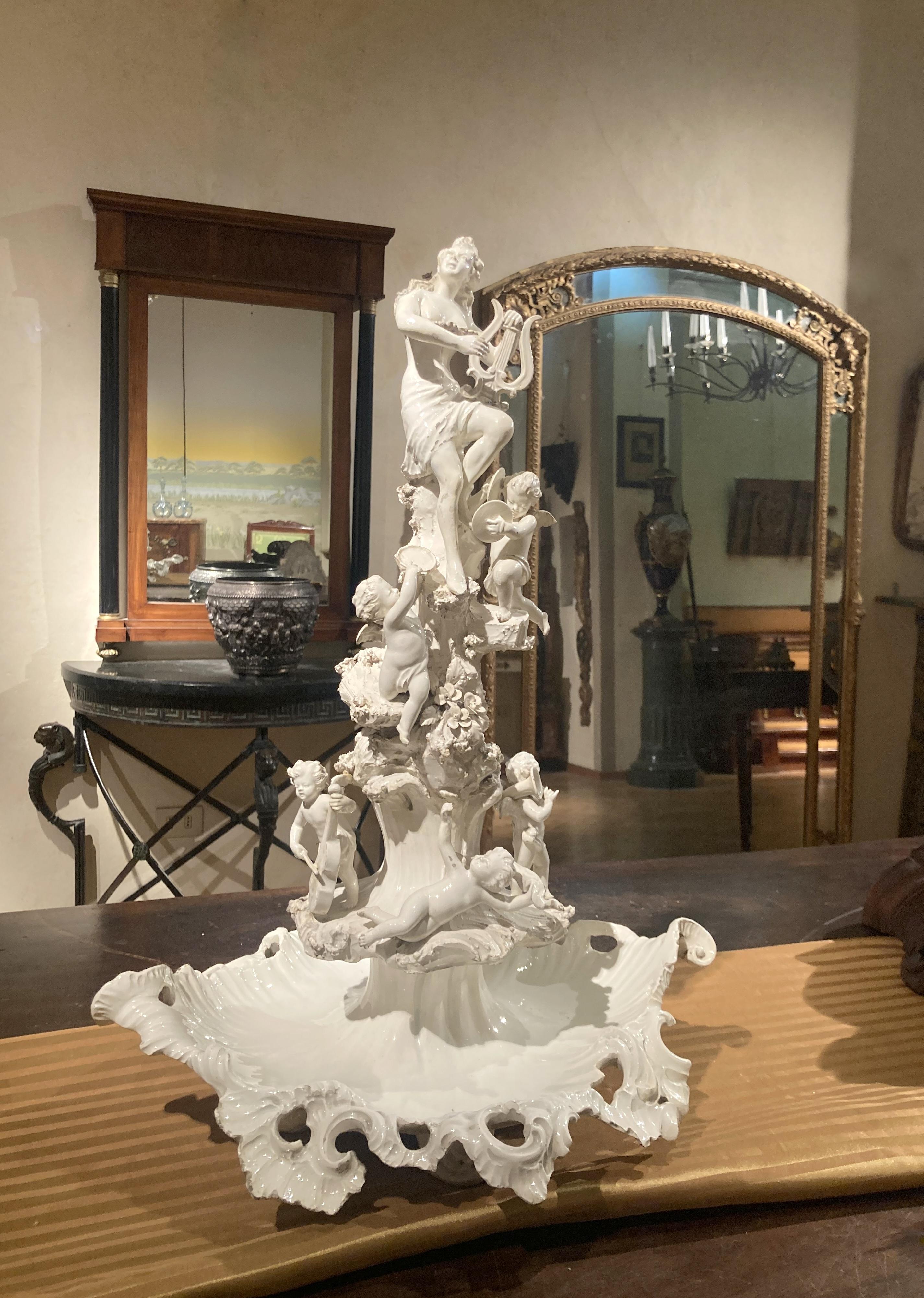This 18th century Italian Capodimonte white glazed porcelain centrepiece is an oustanding sculptural artwork expertly hand carved with finely detailed figurines, putto angels playing various instruments as an allegory of music and elaborate leaves