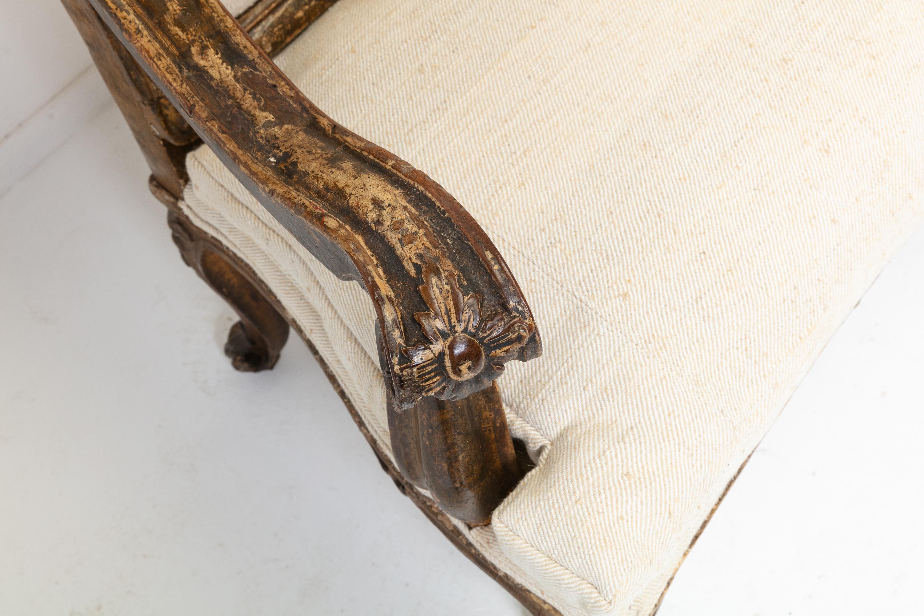 Ein fabelhaftes italienisches vergoldetes Sofa aus dem 18. Jahrhundert mit seiner erstaunlichen, originalen patinierten Holzschnitzerei. Er hat eine geformte, mit Blattwerk verzierte Rückenlehne mit geschnitztem Wappen, geschwungene Armlehnen und
