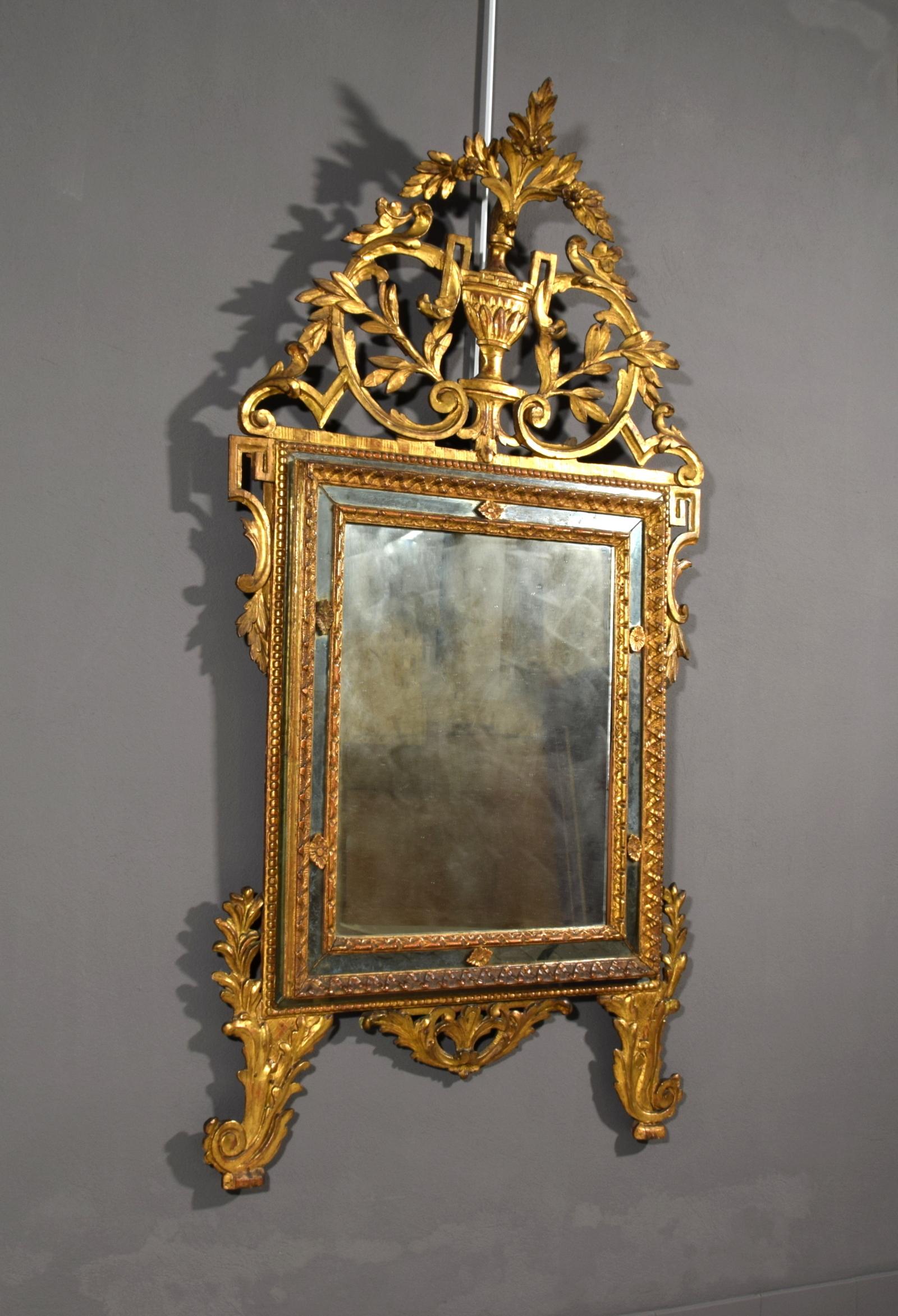 The finely carved, gilded wood mirror was made in Piedmont (northern Italy) in the 18th century.
It has a central rectangular and curved frame, molded and carved with floral and foliated motifs. The frame consists of three concentric sections. The