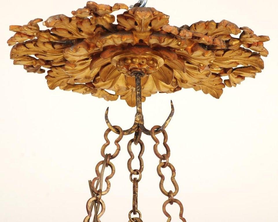 Lustre italien du XVIIIe siècle en bois sculpté et doré avec six bras en fer forgé. Baldaquin en bois sculpté et doré, avec une chaîne d'extension en fer forgé et une coupe en bois sculpté et doré.
