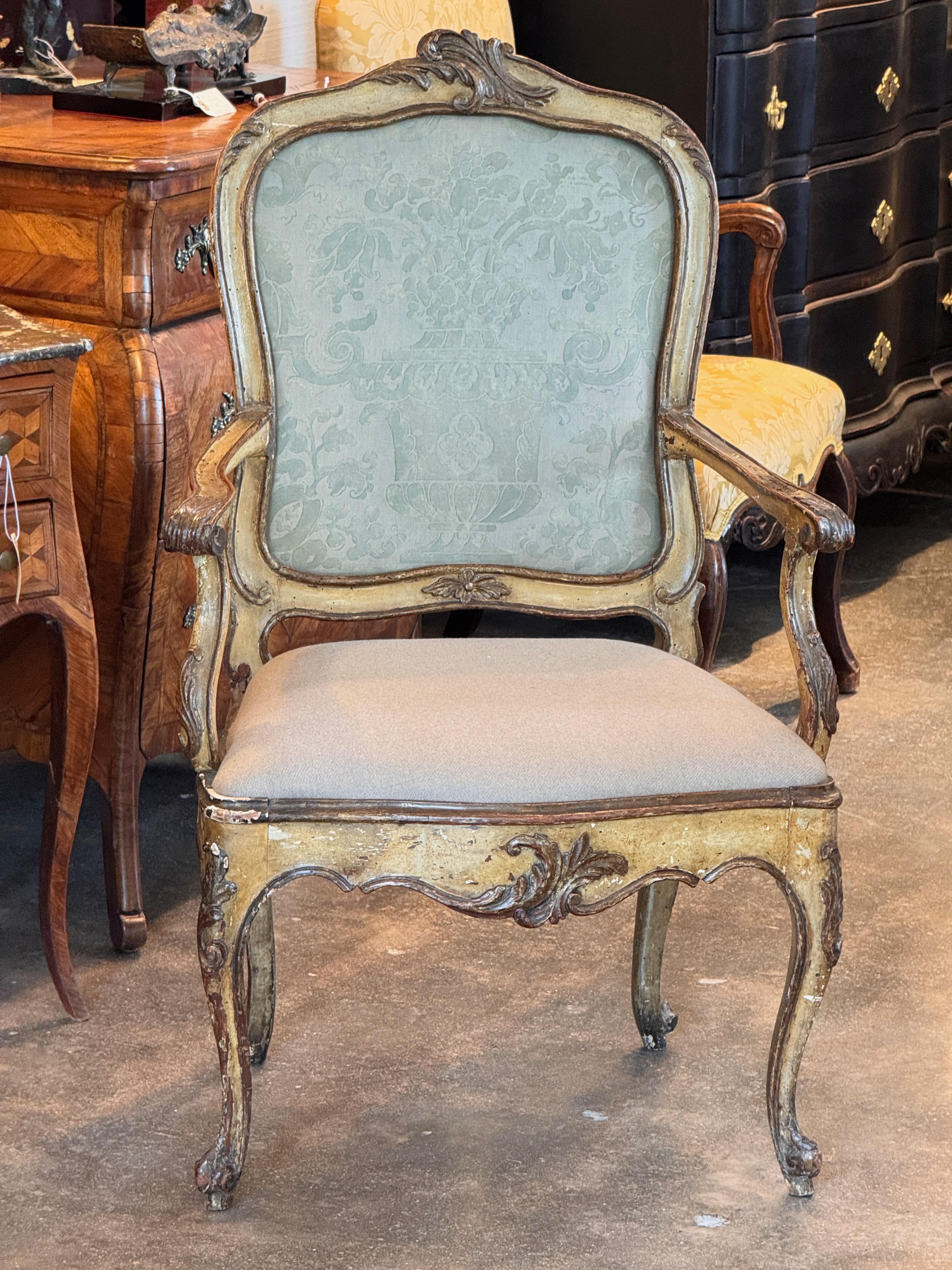 Fauteuil italien du 18ème siècle avec cadre sculpté et tablier serpentin. Le bois conserve une finition peinte usée avec des sous-couches apparentes, ce qui lui confère un caractère vieilli attrayant. Tapissée d'un dossier à motifs vert clair et