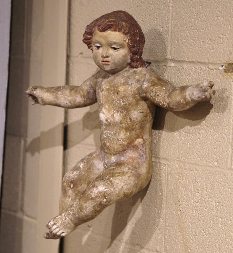 This antique baby Jesus figure was crafted in Italy, circa 1780. The hand-painted putti carving feature its original polychrome finish for a luxurious result. The hand carved cherub with glass eyes, is expressive in it's movement and features a