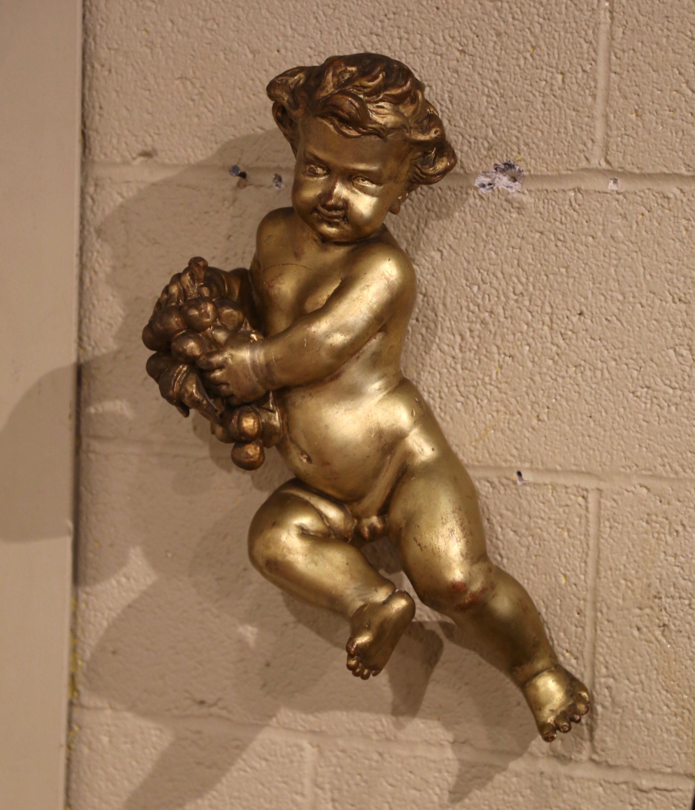 This antique cherub figure was crafted in Italy, circa 1780. Hand carved, the putti carving is shown holding a bunch of grapes in his hands. The cherub is expressive in it's movement and features a wonderful facial and cheerful expression. The