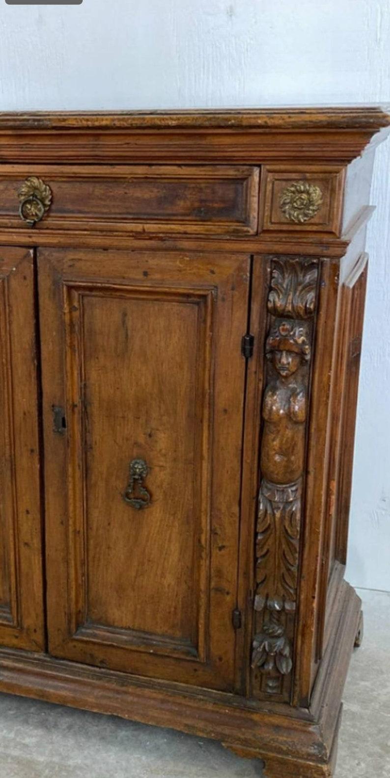 A rare 18th century Italian walnut chest / credenza, Renaissance Period, neoclassical influenced, having two elaborately carved figural statue columns decorated with architectural elements, flanking two cabinet doors, opening to interior fitted with