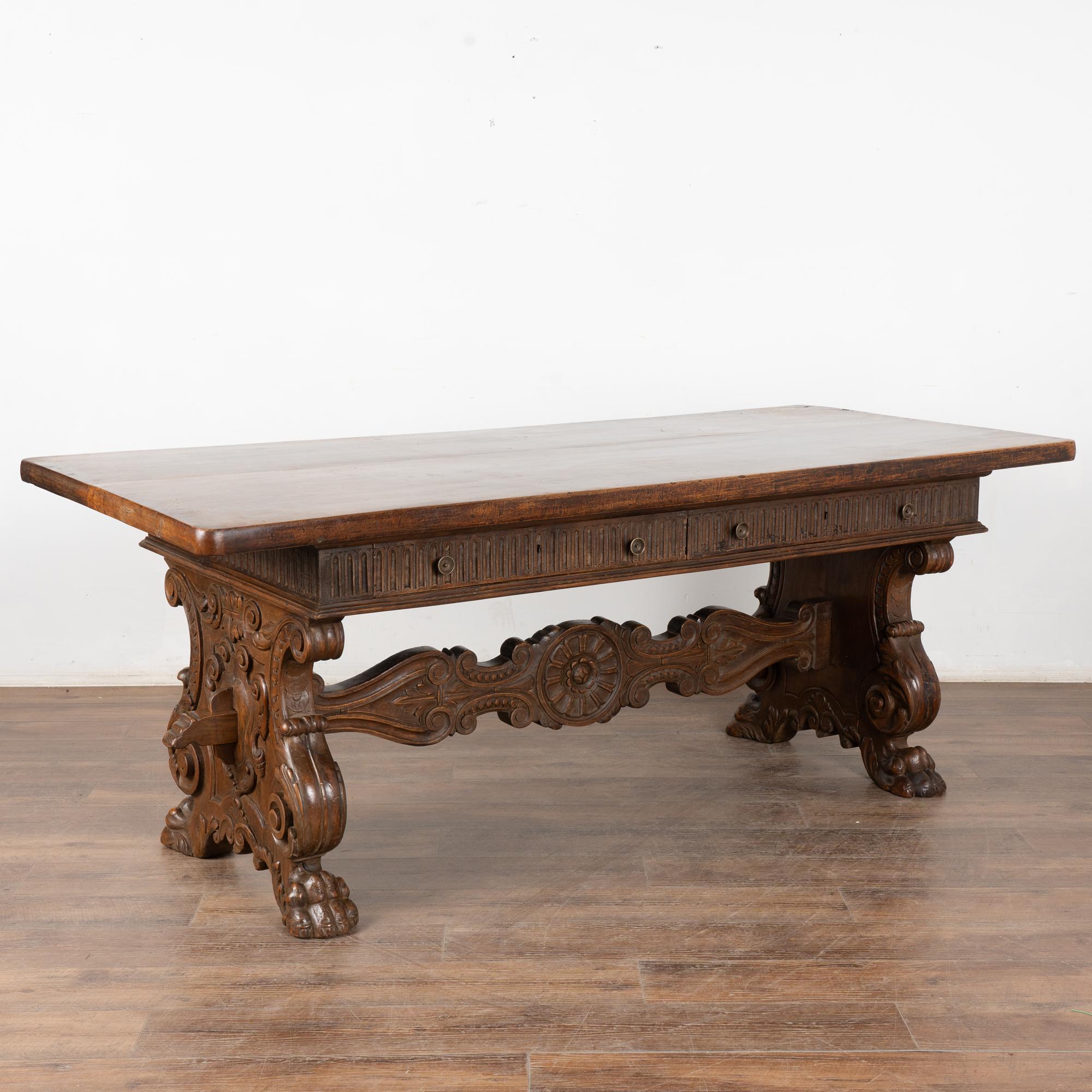 It is the rich, aged patina of the walnut that draws one to this handsome Italian carved desk or console with two functioning drawers.
The heavily carved legs and stretcher are dramatic, while the top reflects generations of use as seen in the rich