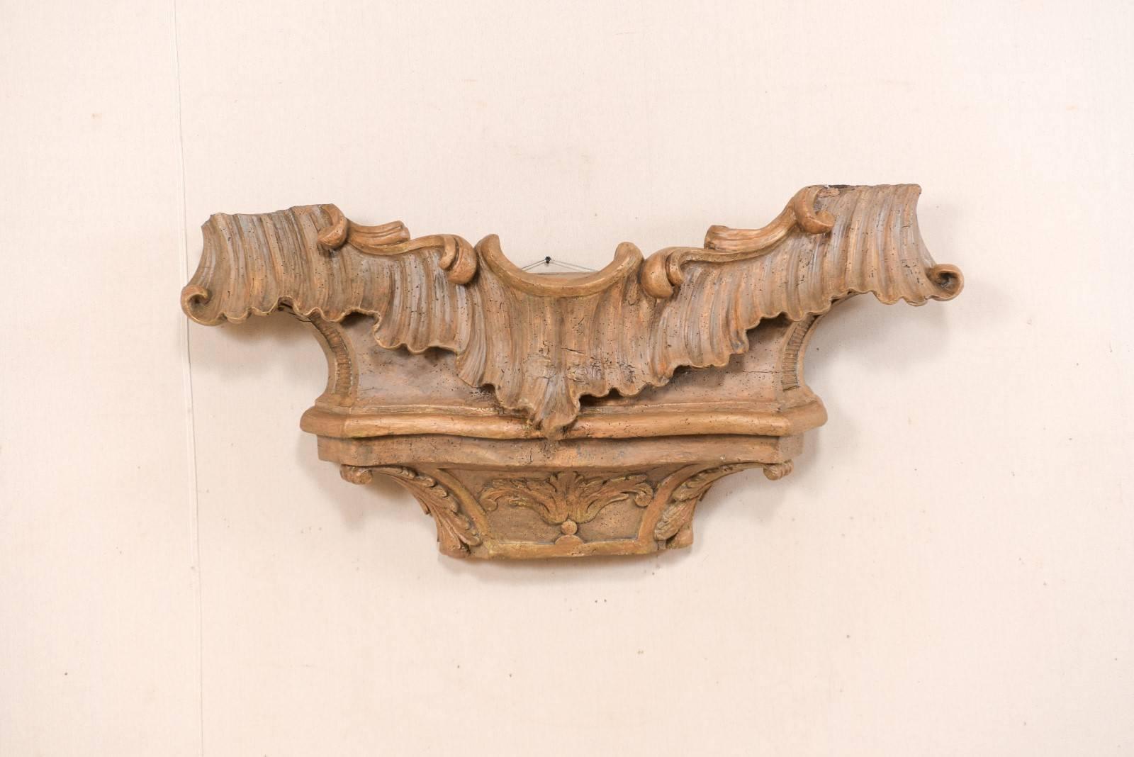 An Italian 18th century wood carved wood wall plaque fragment. This antique Italian wall decoration has a drawn out rectangular shape which is heavily carved in a scroll and acanthus leave motif. The top of the plaque is wider, with a shapely dip at