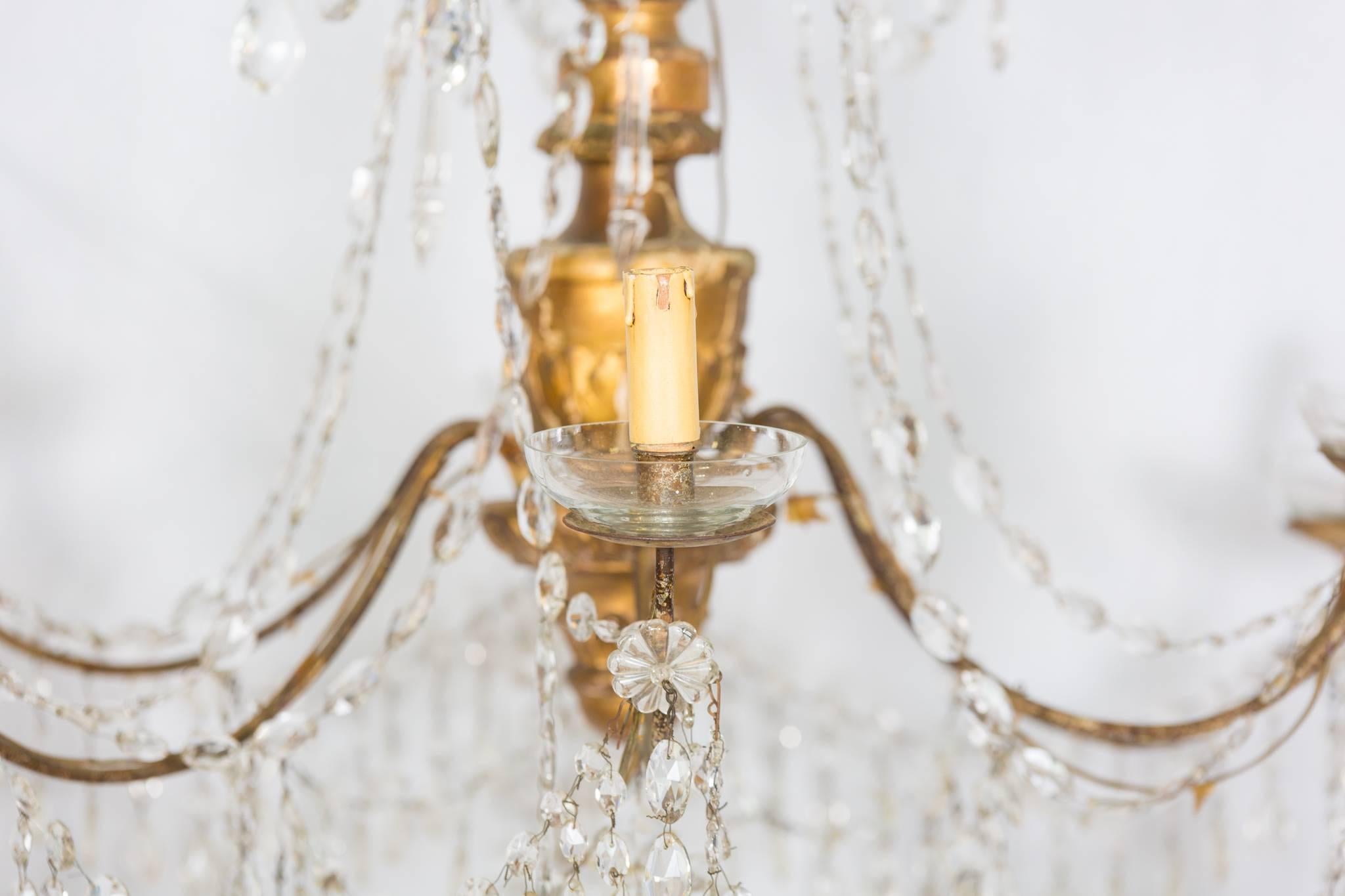 18th Century Italian Gilt and Crystal Chandelier. Dramatic six-light gilded wood chandelier from Genoa, Italy. Beautiful antique crystal and iron detail with crystal rosettes. 