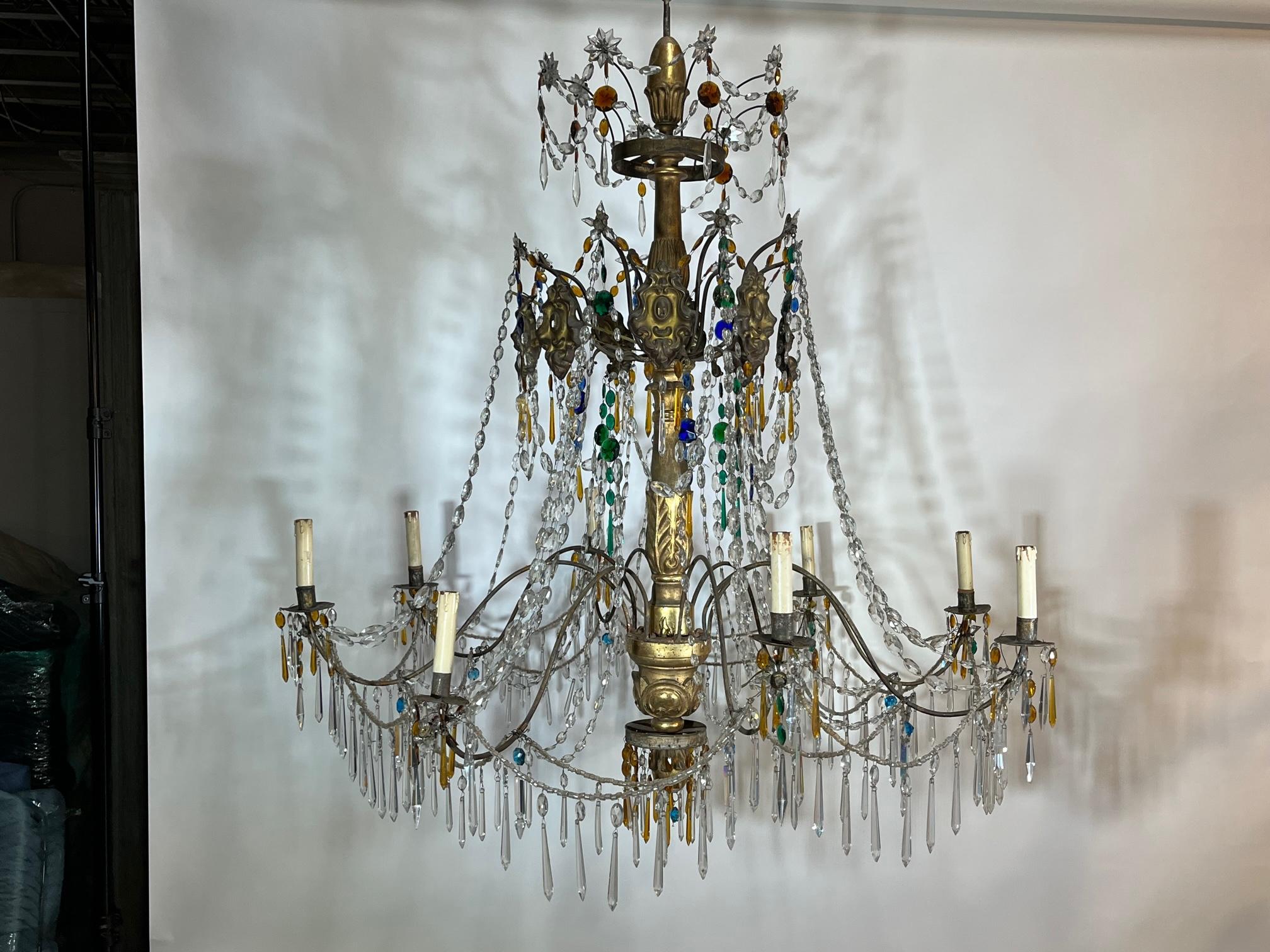 Very fine 18th century Italian large scale chandelier in giltwood, gilt metal and color and clear crystals from Genoa. The chandelier has 8 lights. A stunning piece.