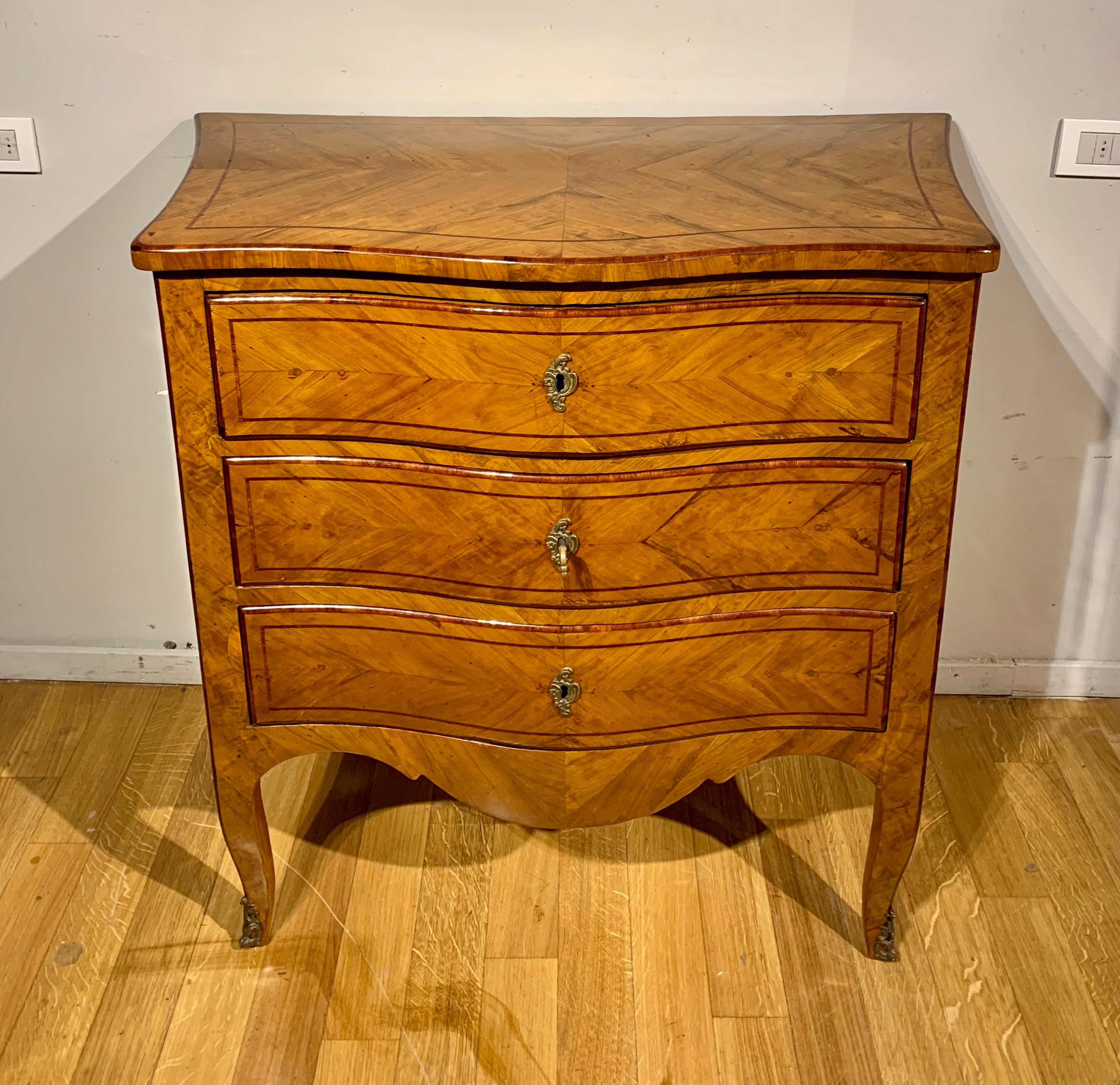 Elegant chest of drawers entirely veneered in olive wood with rosewood and rosewood fillets. Small finishes in lost wax cast bronze, moved on the front and on the sides, it is very roomy and slender thanks to the very slender curved legs. Viterbo
