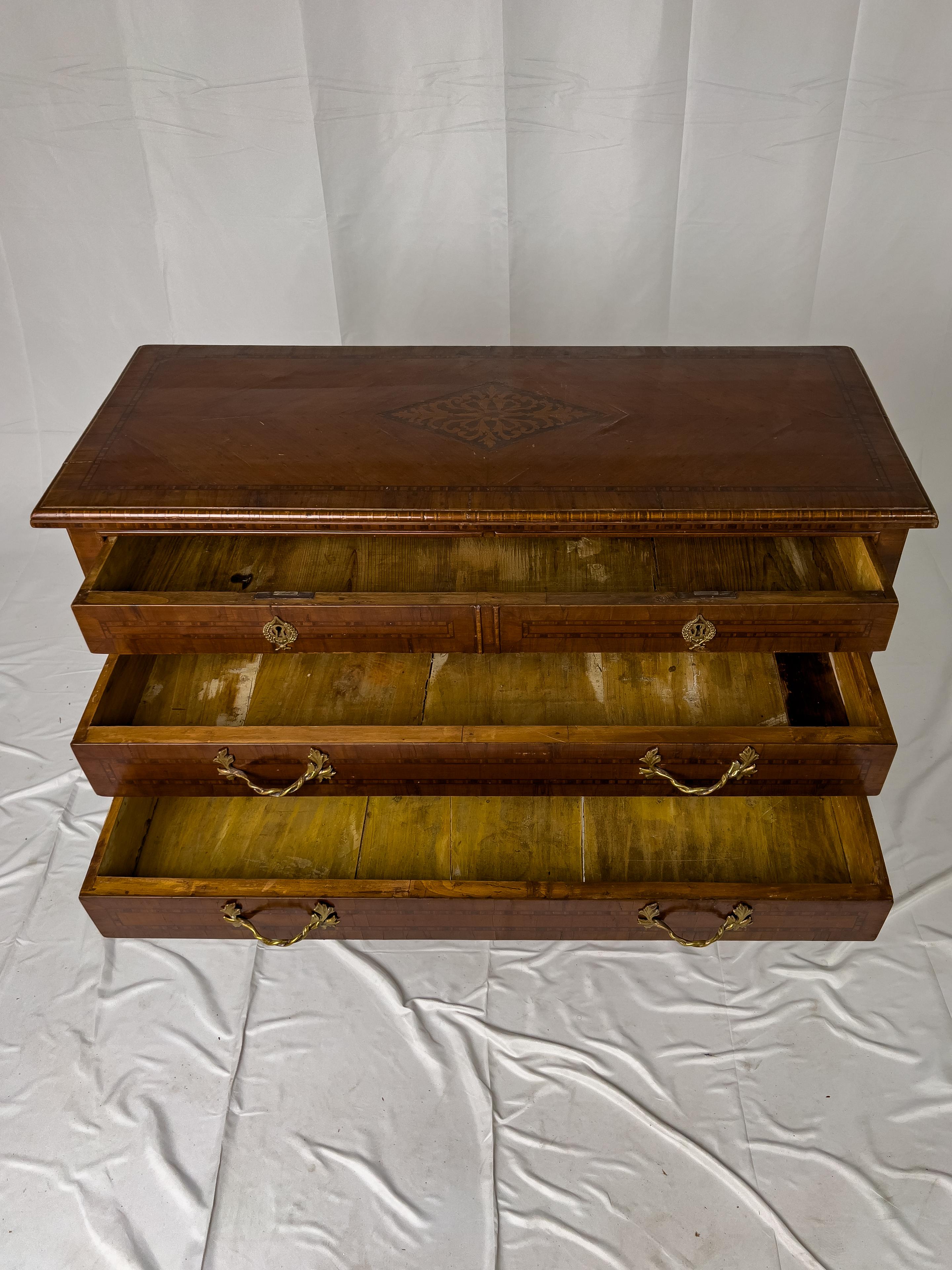 18th Century Italian Commode with marquetry inlay, straight tapered legs, and three drawers (top drawer appears to be two but is really one). The drawers have very unique twisted branch drawer handles, and the top drawer has two escutcheons and two