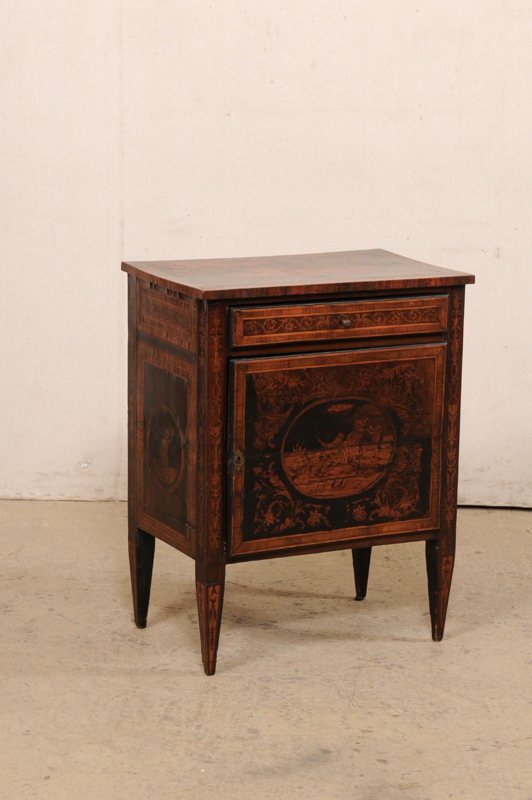 An Italian period Neoclassical small-sized comodino embellished with stunning marquetry, from the 18th century. This antique cabinet from Italy has been elaborately-crafted marquetry inlays about its top and three sides in various designs of