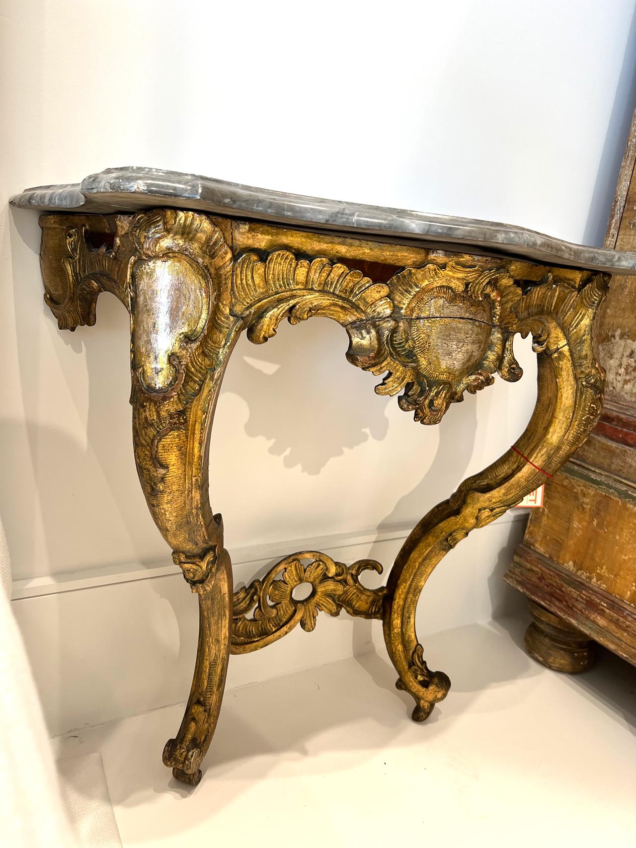 18th century Italian console with grey marble top. Gilded base and marble top console with cartouche carving in center and cabriole legs bring instant grace and beauty in a living room or bedside.