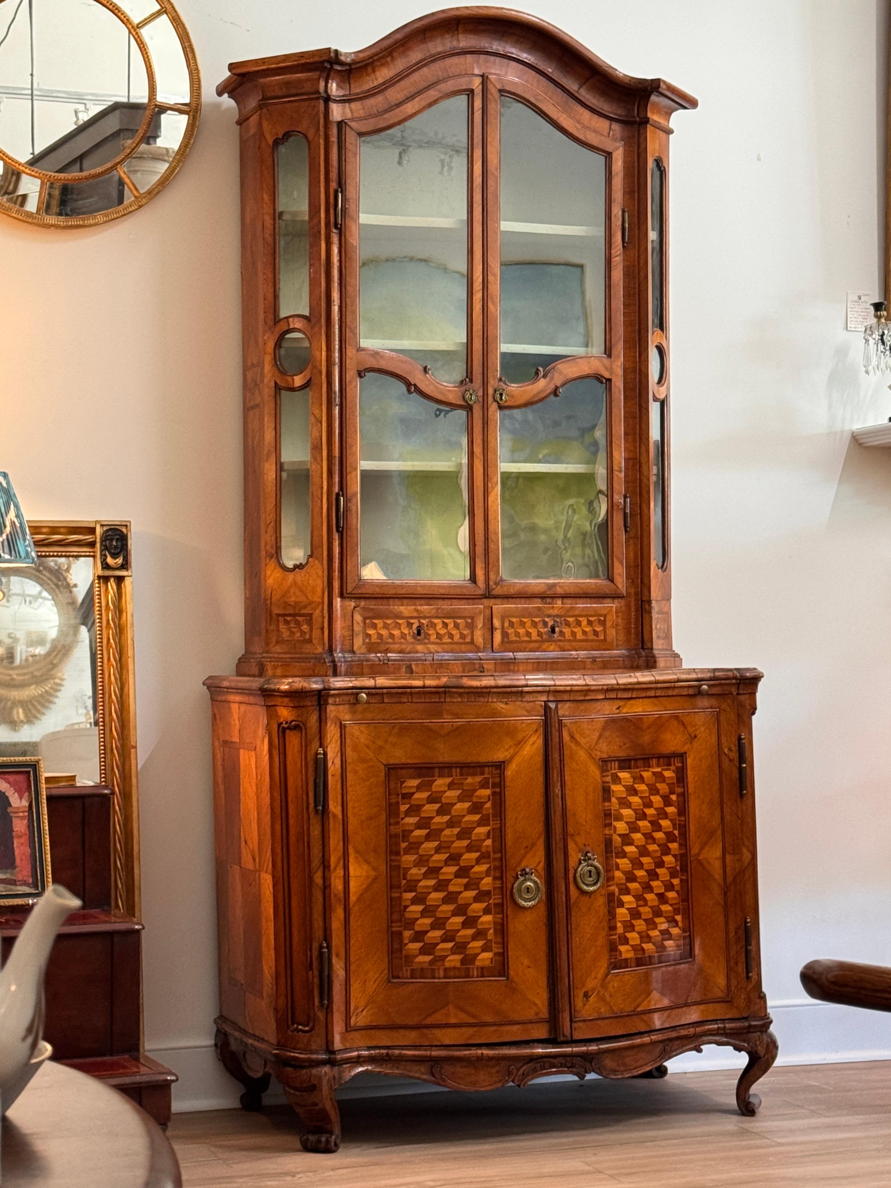 Ein schöner italienischer Bücherschrank aus dem 18. Jahrhundert mit auffälligem Würfelparkett in Nussbaum und Obstholz. Die oberen Glastüren geben den Blick auf bemalte Regale frei, während der untere Teil hinter vertäfelten Türen eine
