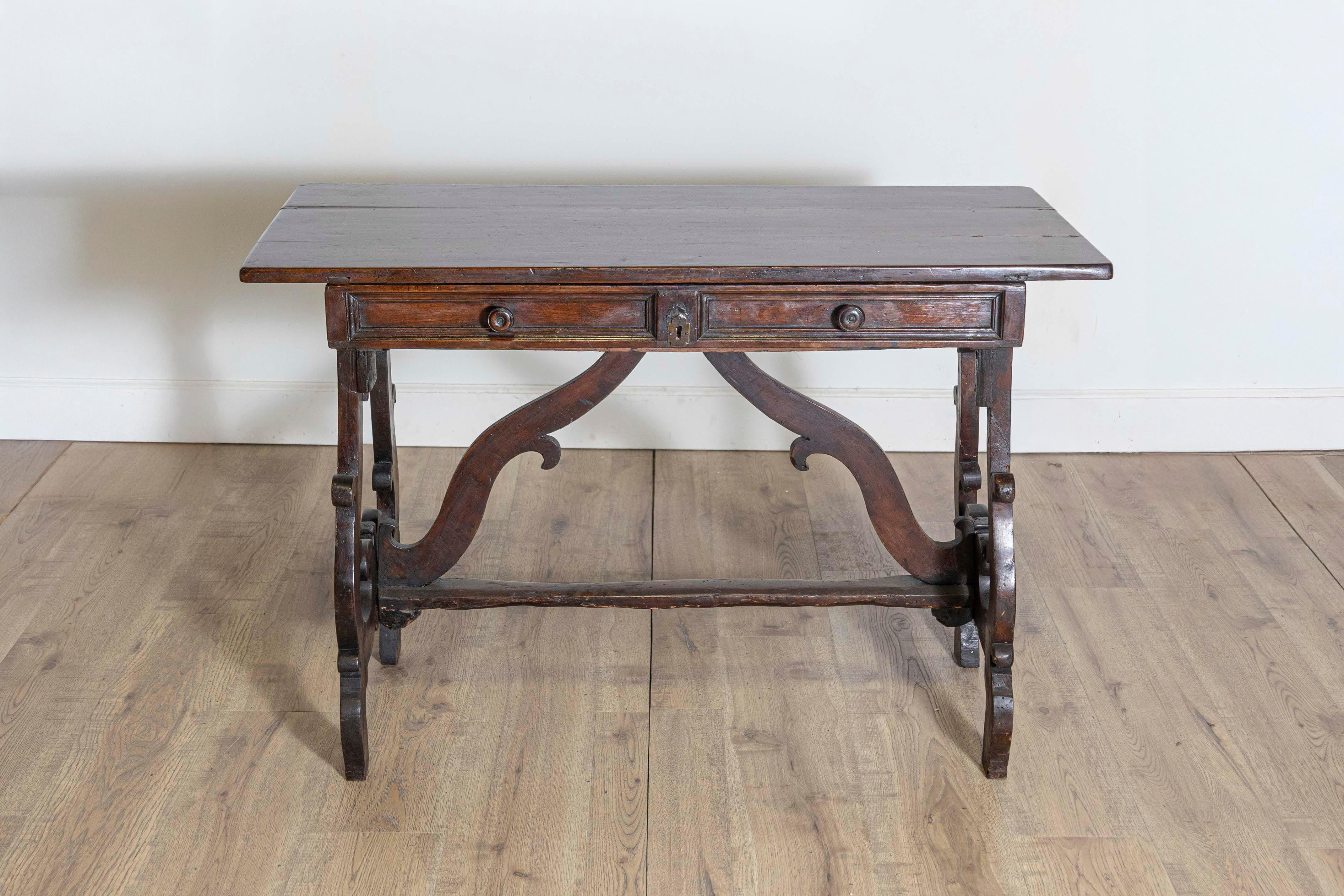 Dieser italienische Schreibtisch aus dem 18. Jahrhundert ist ein Beispiel für die kunstvolle Handwerkskunst und Eleganz der damaligen Möbel. Es ist aus reichem, dunklem Holz, wahrscheinlich Nussbaum, gefertigt und verfügt über kunstvoll geschnitzte