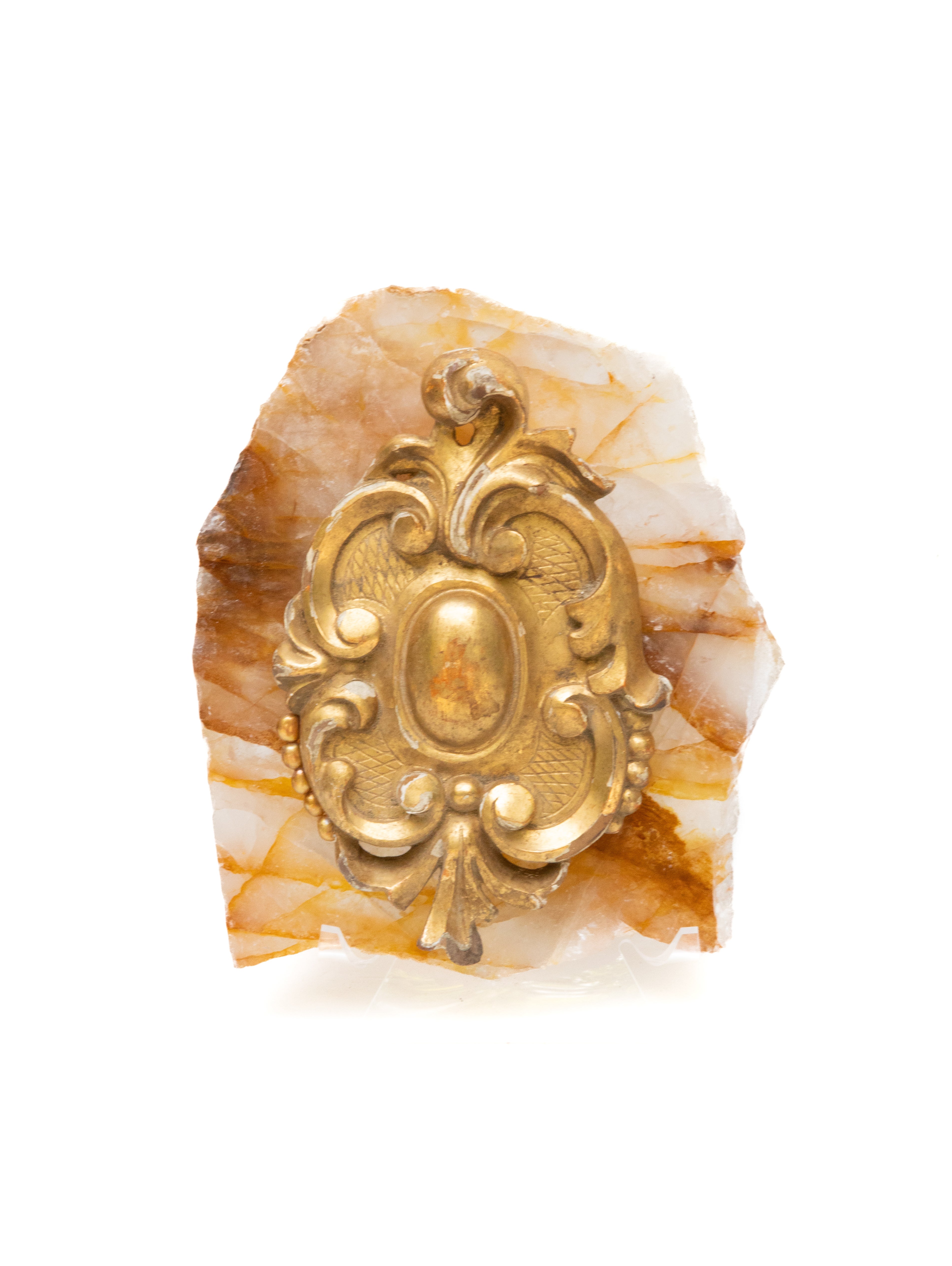 Cresta de fragmento italiano del siglo XVIII, dorada y tallada a mano, montada sobre una losa hematoide dorada y pulida, y adornada con perlas barrocas. El fragmento dorado procedía de una iglesia histórica italiana. Está montada sobre el cristal de