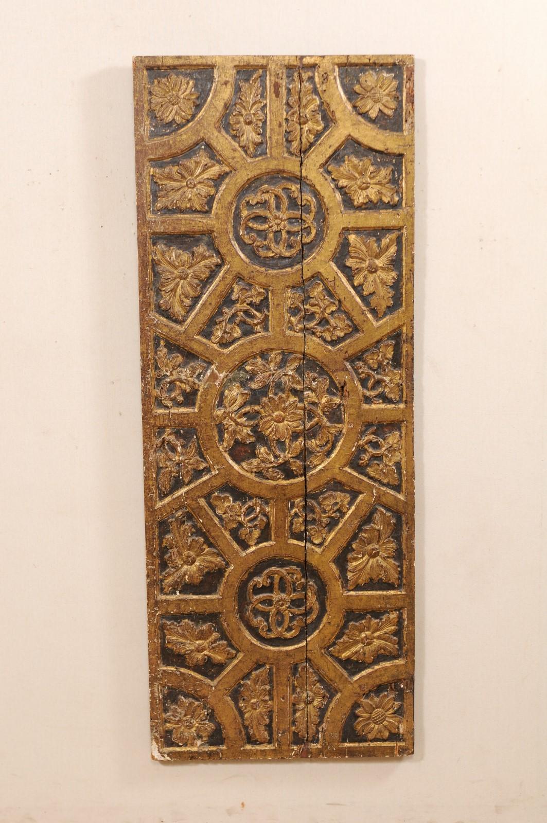 An Italian 18th century gilded and carved wood wall panel. This large size antique hand carved wood panel from Italy features a décor of rinceaux, with floral motif within various geometric panels. This piece is has gilt accents which highlight the