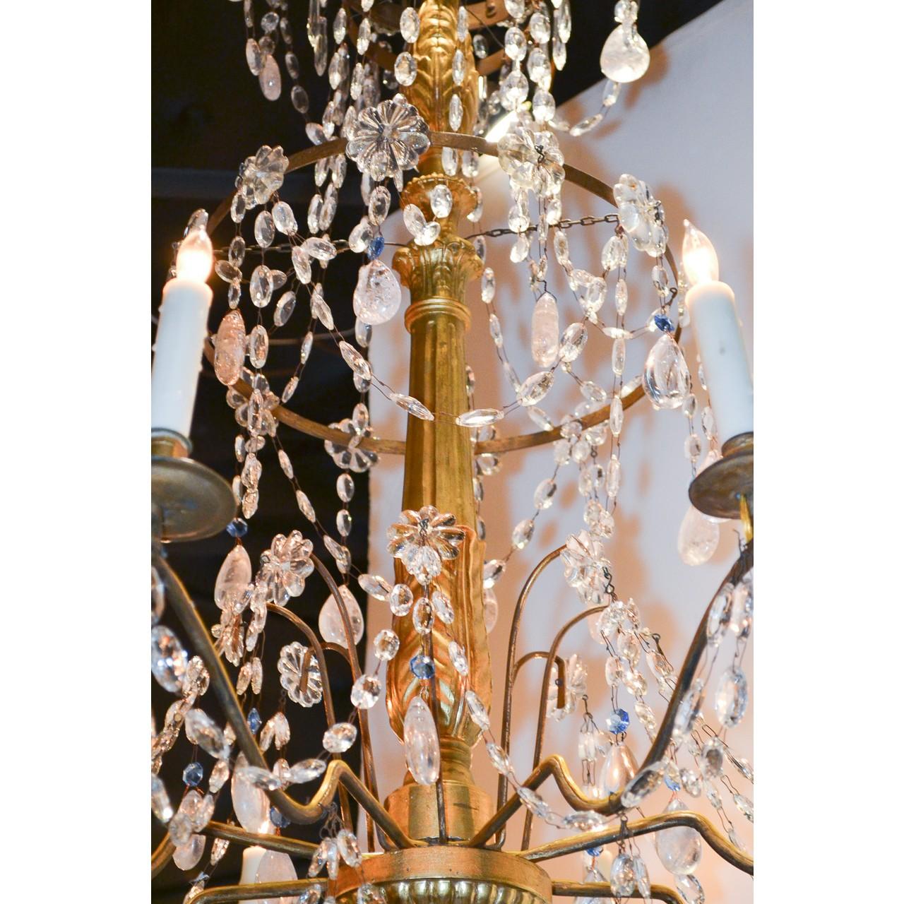 Superb 18th century Italian giltwood and crystal chandelier. The shaped hand-carved stem features three tiers elegantly decorated with almond-shaped crystals, strands of bead crystals, rosettes, and touches of sky-blue crystal accents. The