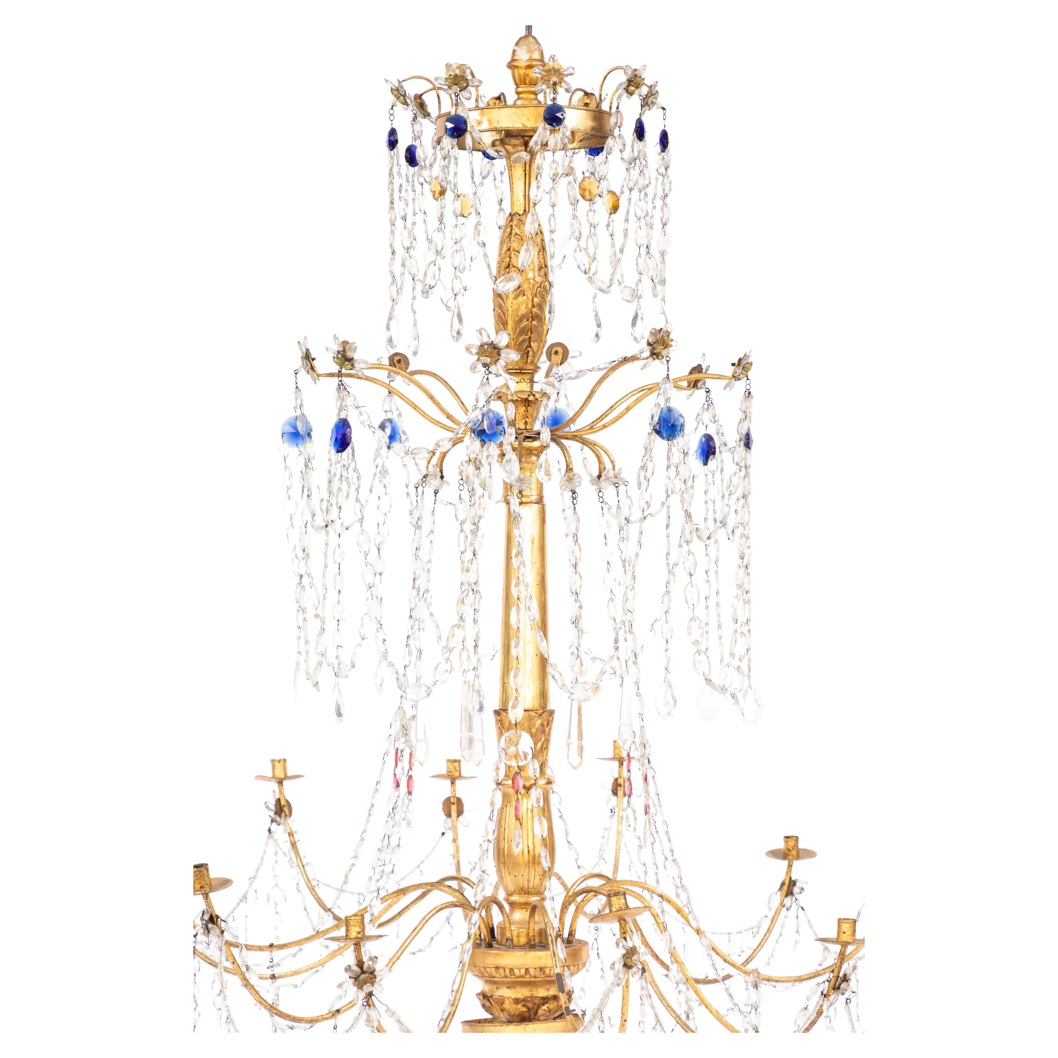  18th century Italian gilt wood and gilded iron chandelier with sapphire and ruby colored crystals. All hand knotted. Candle chandeliers have been electrified.  Pair available.  Some parts are modern, but most parts are antique, Italian elements.