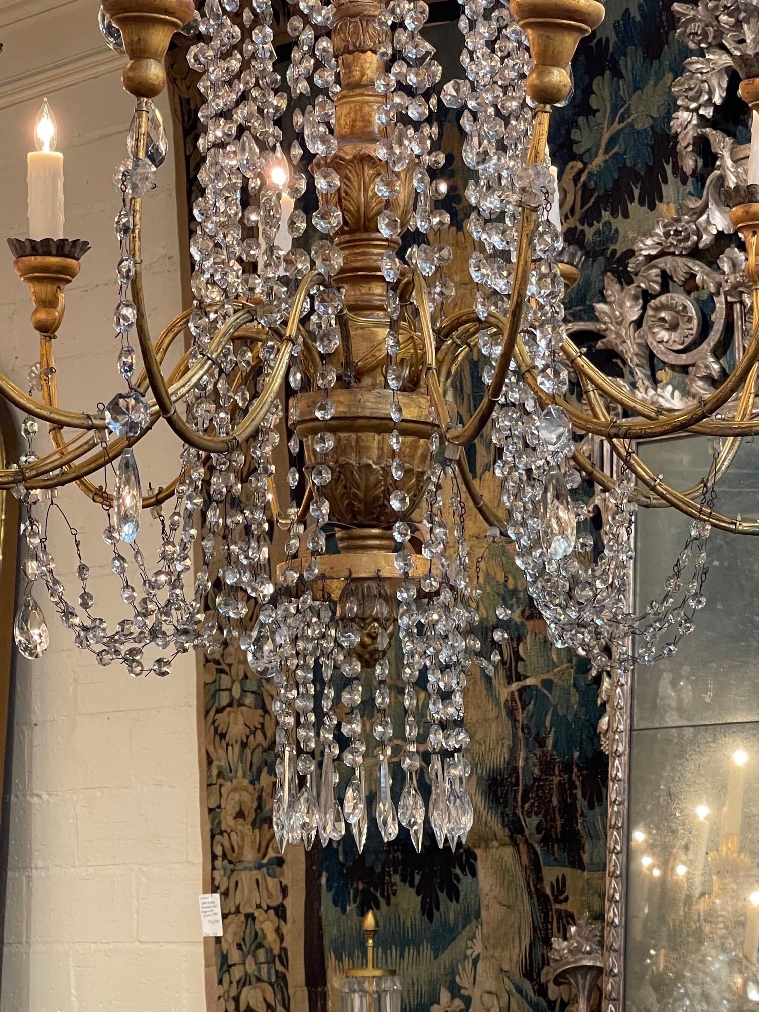 Exquis grand lustre italien du 18ème siècle en bois doré perlé et cristal avec 12 lumières. La base est magnifiquement sculptée et recouverte de superbes perles et cristaux. L'échelle et la forme de cet étonnant luminaire sont remarquables.
