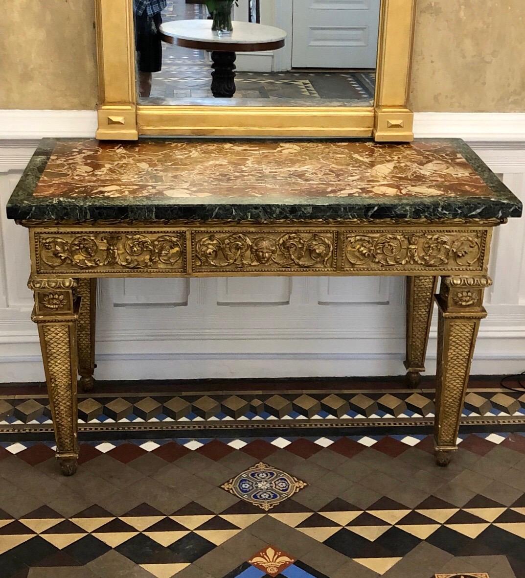 Straordinaria consolle in legno dorato italiano del XVIII secolo con piano in marmo originale. La consolle in legno dorato presenta un fregio frontale intagliato tripartito con una maschera femminile centrale affiancata da foglie che scorrono e